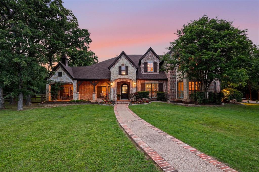 Tucked away at the end of a winding drive, past a peaceful pond that sets the tone the moment you arrive, this one feels like a hidden retreat you didn’t know you were searching for. With 9+ beautifully wooded acres, the setting is pure North Texas charm—quiet, private, and alive with wildlife, towering trees, and trails just waiting to be explored. Completely remodeled and significantly expanded in 2006. 
The home itself wraps you in warmth from the start, beginning with a sprawling front porch made for slow mornings, evening conversations, and everything in between. Inside, natural light pours through dramatic floor-to-ceiling windows, highlighting rich hardwood flooring, stunning fireplaces, and custom built-ins that bring both character and function to every space.
With 7 bedrooms—including 2 conveniently located downstairs—there’s room for everyone to spread out comfortably. Upstairs, the oversized bedrooms feel like their own retreats, with charming lofts and private balconies adding a touch of personality and escape. Four generous living areas create endless flexibility, whether you’re hosting a crowd or carving out quiet corners to unwind. Upstairs game room, media room and more.
The private office is a standout feature all its own—complete with a fireplace, seating area, and abundant built-in storage—making working from home feel anything but routine.
Step outside and the lifestyle really comes to life. Spend afternoons by the beautiful oversized pool and hot tub, challenge friends to a game on your private pickleball court, or cast a line in your own fishing pond. There’s room to roam, space to breathe, and endless opportunities to entertain or simply enjoy the stillness.
A storage building adds practicality. Sought after Argyle and Liberty Christian schools. 
This is luxury living—comfortable, inviting and designed to be lived in and loved. A place where every path leads to something special, and every day feels just a little more like a getaway.