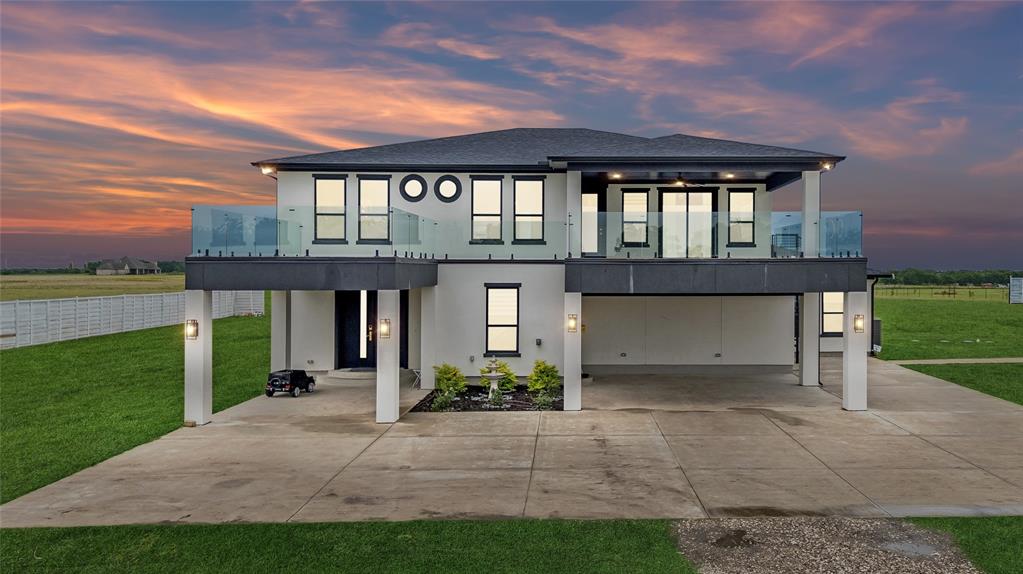 This extraordinary custom luxury estate blends modern elegance, resort-style living, and exceptional functionality. Designed with premium craftsmanship & upscale finishes throughout, the home features soaring ceilings, expansive open-concept living spaces, abundant natural light, and dramatic floor-to-ceiling designer tile accents that create a sophisticated custom-home atmosphere. Built for entertaining, the property includes three spacious balconies — 2 front-facing & 1 rear-facing — creating seamless indoor-outdoor living. One oversized balcony spans approximately 1,200 sq ft with open-to-below visibility & stunning views overlooking the property, while sleek glass railings enhance the home’s contemporary architectural design. The owner’s suite serves as a private retreat with a spa-inspired bathroom featuring floor-to-ceiling tile, rain shower, soaking tub, dual vanities, and a spacious walk-in closet. The gourmet kitchen showcases premium quartz countertops, modern finishes, generous prep space, and an open layout ideal for entertaining & family gatherings. Adjacent is a media & entertainment room with a custom quartz & wood-accented bar. Additional highlights include a spacious utility room with washer-dryer connections, utility sink, and custom finishes. The exterior features a premium perimeter fence with approximately $40,000 invested for added privacy & security, along with nearly 200 strategically planted trees enhancing the property’s natural beauty. A standout feature is the detached approximately 1,800 sq ft insulated & air-conditioned luxury garage-shop retreat located roughly 60ft from the main residence. Designed for vehicle storage, recreation, entertainment, or workshop use, it includes metallic epoxy flooring with approx $20,000 in upgrades, oversized commercial-style doors, a private bathroom, and ample space for multiple vehicles or equipment. A large covered carport accommodates 3 additional vehicles, trailers, boats, or recreational storage.