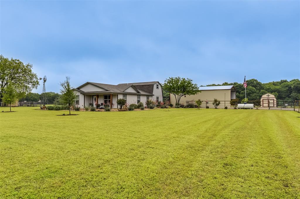 Set on over 2 acres, this well-maintained custom home offers a versatile floor plan with a spacious living room and seamless flow from the kitchen to the dining and living areas. The oversized primary suite is conveniently on the main floor, while two additional bedrooms and a full bath are upstairs. Flexible floor plan with a nice office or hobby room as well--you decide how you want to use this space! Oversized laundry room with storage & extended mud room is handy, too. Enjoy no carpet, fabulous natural light, & abundant storage closets throughout! The half bath downstairs is perfect for guests. Step onto the covered rear porch to relax or utilize for outdoor entertaining. Additional perks include a 50x25 covered parking which is an ideal space for RV or car storage, with an additional RV water & sewer hookup, and a 12x24 storage shed with loft. Refrigerator, mounted tvs, washer and dryer stay! This is a perfect place for buyers seeking space, privacy, low maintenance and practical features all in one home. Pride of ownership shows! County taxes, Waxahachie address & Red Oak schools.
