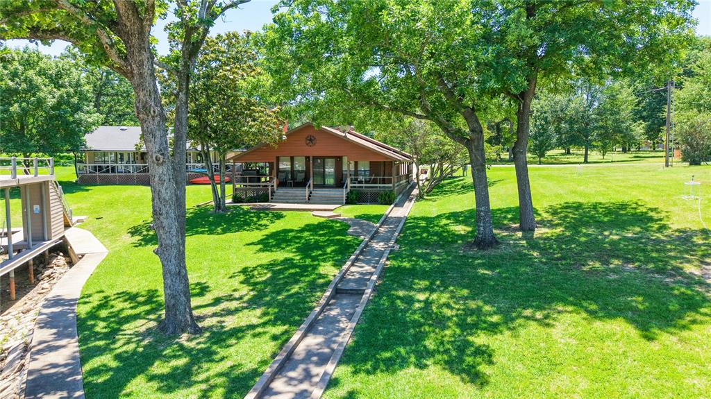 Tucked away in the desirable community of Villa Cove on Cedar Creek Lake, this charming waterfront home sits on two spacious lots with approximately 120 ft. of water frontage, offering additional space for relaxing weekends and entertaining at the lake. The property features a large boathouse complete with two boat slips, a jet ski slip, and an oversized composite cool deck party deck ideal for enjoying sunset views, gathering with friends, or spending long days on the water. Inside, the home offers an inviting open-concept layout with 2 bedrooms and 2 full bathrooms, including a comfortable primary suite . The kitchen features stainless steel appliances, a built-in oven with warming drawer, electric cooktop, high-end granite countertops, and wood-grain porcelain tile flowing throughout the kitchen, dining, and living area. Additional features include a garage, wraparound covered porch, lake pump sprinkler system, and plenty of outdoor space to enjoy. With no mandatory HOA and short-term rentals allowed, this property would make an excellent full-time residence, weekend getaway, or income-producing vacation rental. This is the kind of lake property where memories are made. The extra lot is a blank canvas for your lake lifestyle! Build a guest house, a spacious garage for additional vehicles and storage or a combination of both—whatever fits your vision (within deed restrictions and city zoning). Whether hosting friends, creating a private retreat, or simply expanding your outdoor space. With this flexibility, the property grows with your needs and vision for the perfect waterfront retreat. Additional lot cannot be sold separately.