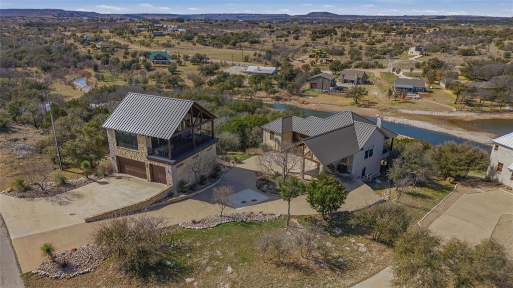 OWNER FINANCING AVAILABLE! Welcome to one of the most coveted places in Texas: Hell’s Gate on Possum Kingdom Lake. From the adrenaline-pumping thrills of Red Bull cliff diving to one of the most amazing firework shows in America, there is truly no place like it. This premier waterfront luxury estate doesn’t just put you near the action; it grants you a front-row seat to the legendary PK lake lifestyle. Set high on the hill of the prestigious Sportsmans World. The heart of this home is the spectacular PARTY ROOM, specifically designed to capture the best view of Hell’s Gate where these world-class festivities take place. This expansive entertaining suite consists of an open living area, dining, and kitchen, all framed by breathtaking vistas. Even the attached full bathroom offers a stunning water view directly from the shower, ensuring you never lose sight of the beauty that surrounds you. For ultimate convenience, a private elevator provides seamless access from the oversized 3-car garage directly into the entertaining quarters.

The main residence is a sanctuary built for hospitality, featuring four large bedrooms and three well-appointed bathrooms that comfortably sleep 8+ people for unforgettable family get-togethers. The interior ambiance is anchored by a stately fireplace in the main living area, creating the perfect atmosphere to cozy up during cooler Texas evenings. Transitioning to the outdoors is effortless, with both an upper patio and a lower patio providing multiple levels for relaxation and taking in the lake breeze. For those who thrive in the fresh air, the property features an inviting outdoor fire pit perfect for cooking over an open flame or simply unwinding under the stars. At the water’s edge, you will find a dedicated area to bring your boat, paddleboards, or kayaks for a day or a weekend on the lake. There is truly so much to offer in this lakeside retreat. It comes fully furnished for the turn key, instant lake life!