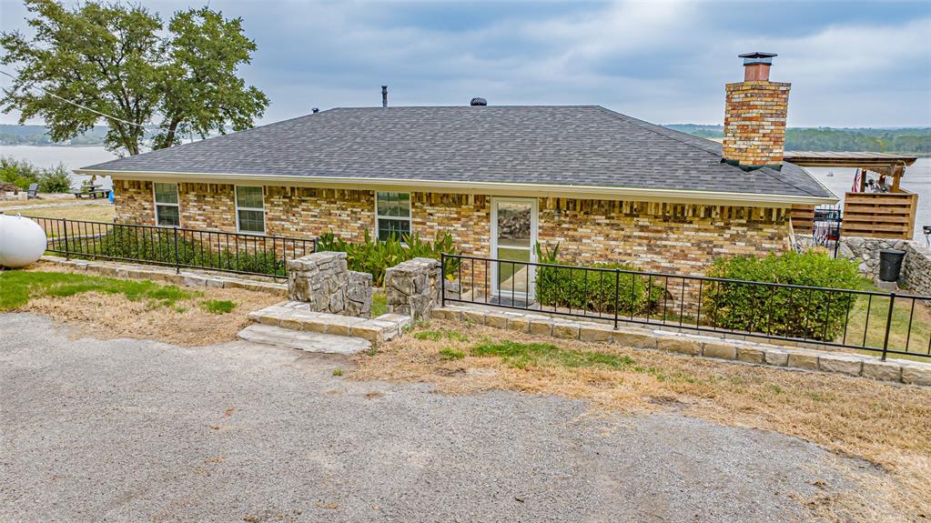 VIEW, VIEW, VIEW - This is the perfect place to kick back and enjoy the Lake Granbury on this main body location. The open living, dining, kitchen area are accented by a wall of windows along back for a spectacular view. The stone fireplace, rustic tile flooring and oversize custom Oak island for dining set the tone for the living area. The backyard is perfect for entertaining with a covered patio, pergola, & hot tub all overlooking the lake. Electric tram down to the covered boat with lift. Located in a private, gated community only minutes from town, restaurants and shopping. Come make this crown jewel your getaway or full time home.