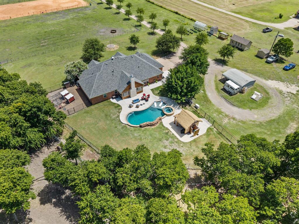 Welcome to your dream property -This exquisitely renovated 10 +acre luxury home combining country living with resort style amenities. This beautifully updated 3-bedroom, 2 and a half bath home, features new luxury vinyl plank flooring throughout the main living areas, renovated bathrooms. The gourmet kitchen boasts tons of natural light and a spacious breakfast area, along with quartz countertops, stainless steel appliances, double oven, farm house sink, new cooktop, pot filler, large walk in pantry. An elegant formal dining room with upgraded lighting provides the perfect setting for gatherings. A dedicated home office offers flexibility for remote work.This exceptional property includes a professionally designed 100 x 200 riding arena with premium Brazos River screened sand, professional fencing, and arena gates—perfect for recreation or training. The fully enclosed 60 x 40 barn features 7 stalls with performance-grade fans, dedicated 200 amp service, climate controlled tack room, wash area, and sliding doors for easy access.Professionally landscaped with multiple irrigation zones, dual water sources for pastures and greenhouse, two greenhouses, and multiple storage sheds including a climate-controlled 10 x 20 shed with heat-AC and electrical service—perfect for hobbies, and storage. Additional garden and storage sheds, large dog run, chicken coup, underground storm shelter and extensive fencing throughout. The property's thoughtful infrastructure supports multiple animals and diverse lifestyle possibilities. An 8-ft deep swimming pool with spa, waterfall, gas heater, and commercial chiller featuring an oversized tanning ledge. A stunning palapa bar with ceiling fan, TV, full-service island with sink & utilities, and outdoor shower. Spacious deck and patio areas perfect for entertaining.Conveniently located less than 15 minutes to downtown Waxahachie, offering easy access to shopping, dining, and entertainment while maintaining peaceful country living.