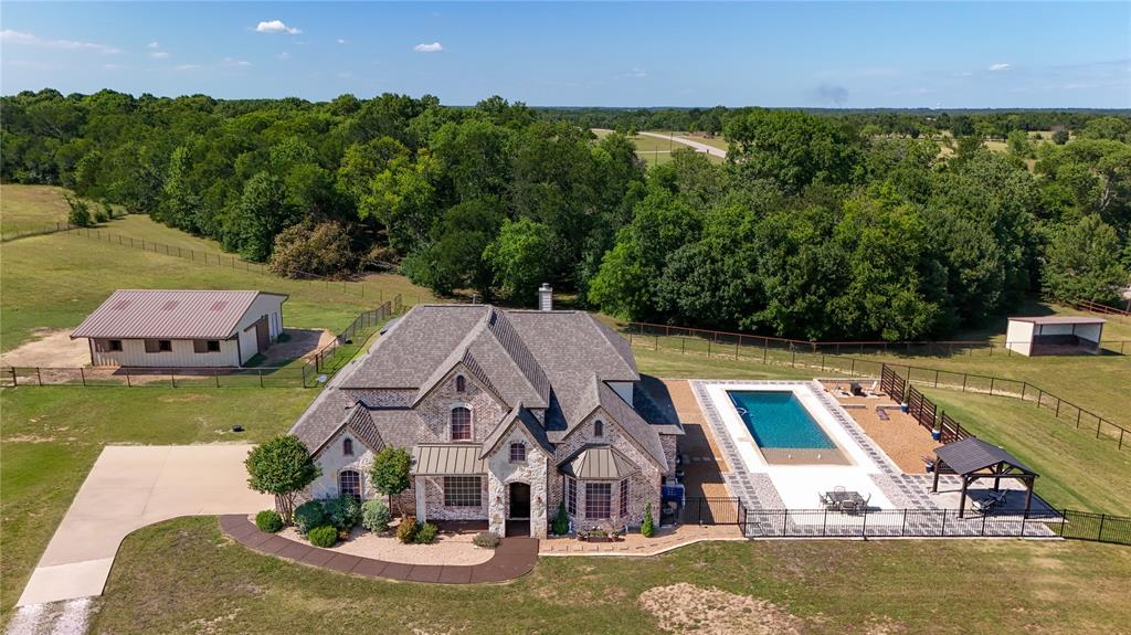 Luxury Horse Property on 10 acres with pool just 40 miles North of Dallas. This beautiful home has recently been refreshed with new paint and a new roof installed. The interior paint gives this home a bright & refreshed feel.  Immaculate 4-bedroom, 2 full bath, 2 half bath home on 10 acres designed for comfort, quality, and equestrian living. This property offers a rare combination of luxury amenities, thoughtful construction, and functional ranch features.
The home was built with 2x6 framing, hurricane rafters, extra attic insulation, and an engineered foundation with piers drilled to bedrock. Inside, the open and inviting layout includes a media room with theater seating, noise-canceling panels, and a movie screen, a spacious game room ideal for pool or poker, and a dedicated office. The primary suite features a garden tub creating a spa like retreat.
Outdoor amenities are exceptional. The property features a barn with a tack room and  8-foot center aisle, a 3-rail, 5-foot perimeter pipe fence, and cross-fencing throughout. A creek runs through the property, with a cleared area perfect for a playground or additional recreational space.
The backyard offers resort-style living with a pool featuring a beach entry that gradually deepens to 8 feet, surrounded by landscaping, a decorative privacy fence, and a fire pit for entertaining. Additional features include a dog run and a storage shed.
This property provides the perfect blend of refined living and equestrian functionality in a peaceful country setting.