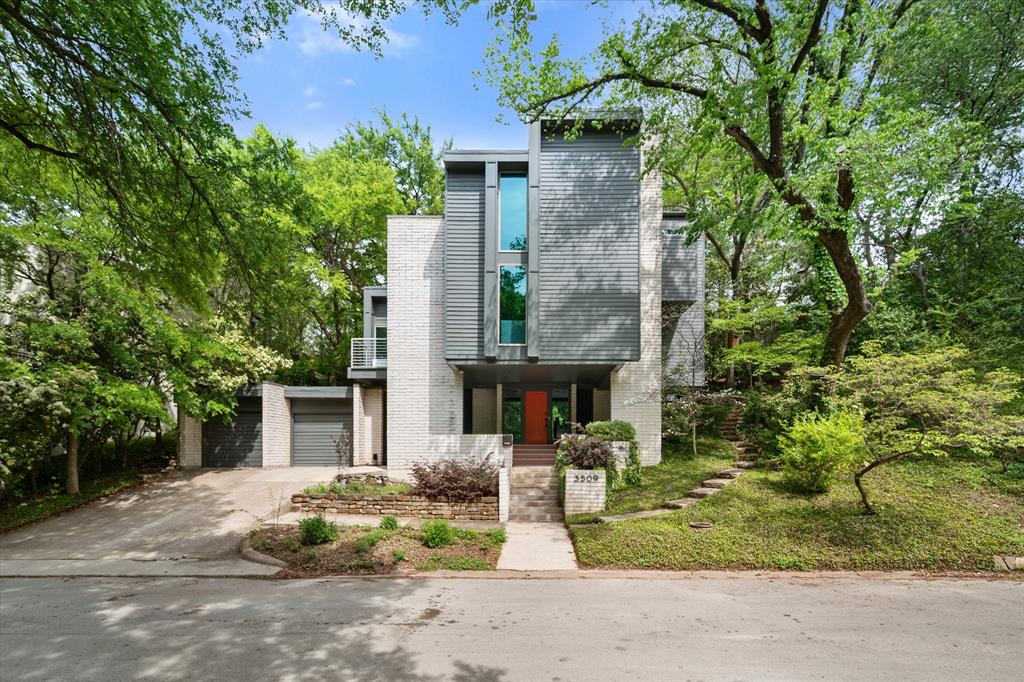 Set into the trees just moments from Overton Park and TCU, 3509 Bellaire Park Court is a three-story architectural home that does things differently. An intriguing blend of modern and brutalist design, it stands out as one of the more unique homes in Fort Worth—defined by clean lines, intentional scale, and a private, tree-filled setting at the end of a quiet cul-de-sac.

Inside, the living room is anchored by a large wood-burning fireplace and framed by views of the surrounding canopy. The dining room features a full wall of windows looking straight into the trees, bringing in natural light and creating a setting that feels both elevated and inviting. The updated kitchen offers a fresh, clean palette with stainless steel appliances, ample prep space, generous storage, and a breakfast area with direct access to the backyard.

Upstairs, the primary suite is spacious and private, complete with its own fireplace. The bath is bright and well-appointed with dual sinks, a makeup vanity, soaking tub, separate shower, and a walk-in closet. The home is completed by two additional bedrooms and a full bath on the third level, a two-car garage, and a treetop office with a private balcony.