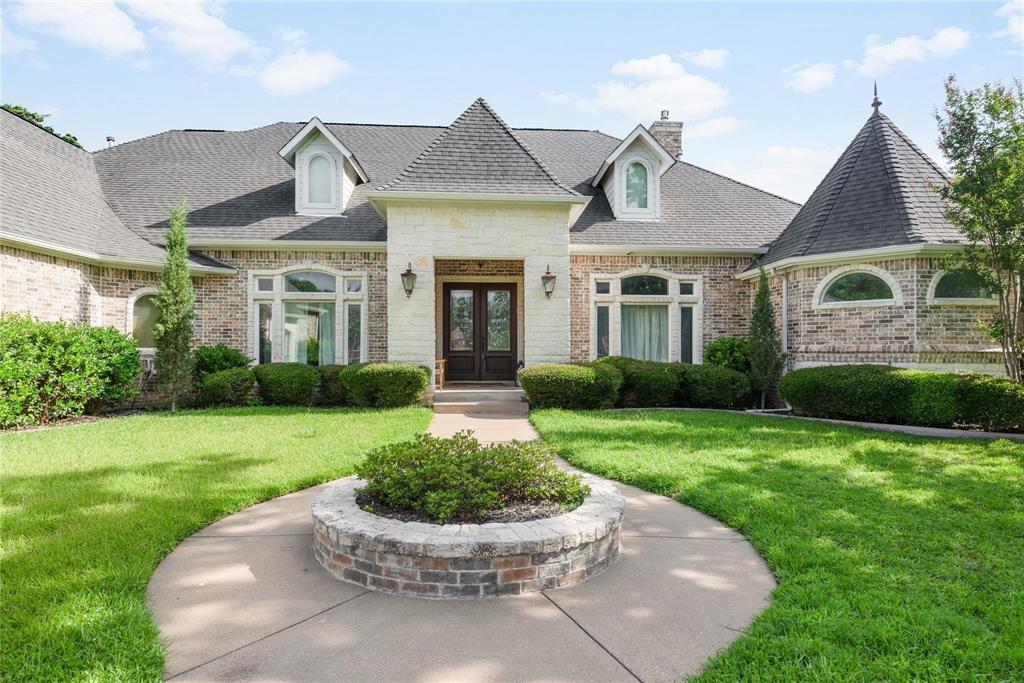Luxury, privacy & resort-style living await in this beautifully maintained 4-bedroom, 3-bath custom home offering 2 living & 2 dining spaces & 3-car garage situated on 1.49 acres. A grand entry welcomes you with a mosaic tile inlay, soaring ceilings & natural light. Formal living & dining spaces showcase Brazilian hardwood floors, architectural columns & timeless finishes, ideal for entertaining or everyday living. The heart is spacious family room featuring a gas fireplace & expansive view of the private, heavily treed backyard & resort-style pool. The adjoining kitchen is thoughtfully designed with granite countertops, center island, breakfast bar, gas cooktop, double ovens & Sub-Zero refrigerator. The primary suite offers a private retreat with hardwood flooring, gas fireplace & serene views of the pool & backyard. The spa-inspired en suite bath features a double shower, jetted garden tub, dual vanities & generous walk-in closet with a private courtyard, adding a tranquil, resort-like touch. A private 4th bedroom or office with built-in shelving is conveniently located on the main level, offering excellent flexibility for guests or remote work. There is a well-appointed laundry room with sink & storage & a pool bath with direct access to outdoor living areas. Upstairs, a large game room with half bath provides even more versatility. Step outside to enjoy outdoor living & privacy. The backyard is designed for both relaxation & entertainment, featuring a sparkling saltwater pool with waterfall, deep end diving, sun ledge & expansive decking. An extended covered patio includes a built-in grill with granite prep area, making it perfect for gatherings. Amenities include a bocce court, greenhouse, garden areas, fruit trees & lush landscaping for a sense of seclusion. Separate 15×15 outbuilding offers flexibility for use as a gym, office, art studio, hobby space, or guest retreat. The property also features hard-wired fiber optic internet. No city taxes. Mansfield ISD.