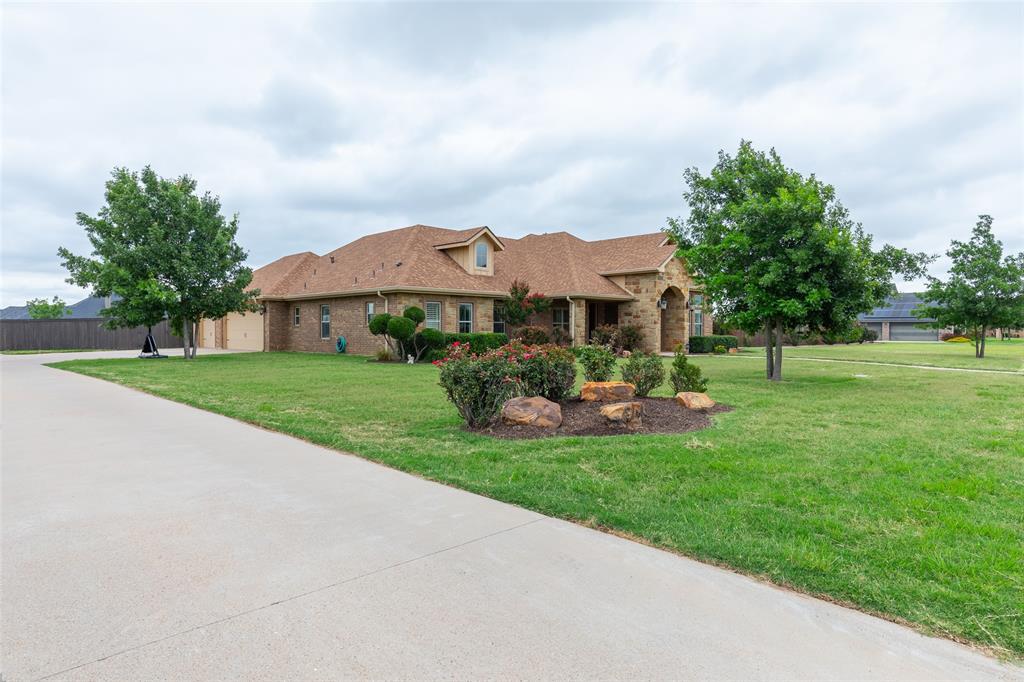 Outside the city limits in the popular  upscale Hacienda Ranch subdivision.  Abilene Wylie ISD.  This exquisite  home was built with many extra amenities in 2014.  Established landscaped yard in just over a half acre of land. Stone and brick exterior with ample  driveway for extra toys or cars plus a 3 car side entry garage.  Home features a front formal dining that opens into kitchen and den. Living room features  a vaulted ceiling with a stone fireplace and wood beams. Custom kitchen with double oven, floating  granite island,custom cabinetry, walk in pantry.  Den and dining features windows across back of house overlooking back patio.  Primary suite  with separate tiled shower,  his and her sinks, floating tub and walk in closet.  Split bedrooms   . All bedrooms nice sized with walk in closets.  Utility room features ample custom cabinets and sink. Built in desk with bookcase  is a plus..Extras include Foam insulation, two recirculating water heaters, 15.5 seer AC, roof replaced 3 years ago., covered patio with exterior fireplace. overlooks large fenced backyard.
Location, Subdivision, School and price is all a plus in this Abilene Texas home.  Our market is strong. Don't delay ! Make this your new home in West Texas !!