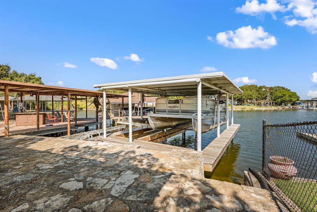 LAKEFRONT living at its finest!! Looking for a home right on the lake? This home checks all the boxes. A major highlight of this property is the fully updated private boat dock, featuring a boat lift plus a separate tandem jet ski lift- all upgraded just two years ago with new wood, cover, lift mechanisms and more. (a 23k investment.) Whether you love boating, fishing, kayaking, or simply relaxing by the water, this lakeside setup is ready to enjoy. There is plenty of covered entertaining space on the patio just steps away from the waters edge. This beautiful maintained 2 bedroom, 2 bath lakehouse overlooks the serene waters of Lake Granbury. Wake up to breathtaking sunrises that paint the sky right outside your window and enjoy peaceful evenings on your private dock. This cozy yet spacious home blends comfort and tranquility, offering an ideal escape for weekend getaways or full time lakeside living. The open concept layout provides seemless flow between the living, kitchen and sunroom areas. Downstairs offers an additional BONUS 624 sqft with a large family room and full bath. Perfect for entertaining or quiet evenings at home. Conveniently located close to Glen Rose and downtown Granbury. Canyon Creek is nestled within a private, gated and guarded communtiy offering exceptional amenities and piece of mind. Turn your dream of paradise into reality. Don't miss out!  ***With use of sellers preferred lender, buyer may receive up to 1% of the sales price towards closing costs. Some exclusions apply. Reach out for more details. ***
