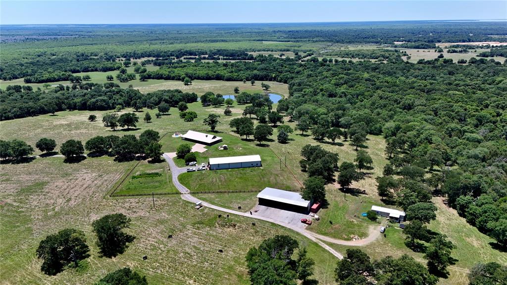 Nestled atop the highest point of approximately 140 picturesque acres, this exceptional ranch offers sweeping views, unmatched privacy, and the perfect blend of comfortable country living and working ranch functionality. The diverse landscape features open meadows, scattered mature trees, dense wooded areas, and nearly two acres of spring-fed lakes that attract abundant wildlife and create a peaceful natural setting.  At the heart of the property sits a beautifully positioned four-bedroom, three-and-a-half-bath ranch home designed to capture the stunning vistas from every angle. The spacious living area opens to expansive wrap-around covered porches, creating the ideal setting for relaxing, entertaining, or simply enjoying the breathtaking scenery and tranquil surroundings.  Complementing the main residence is a versatile barndominium featuring one bedroom, one bath, a living area, kitchen, office space, and an attached spacious barn—perfect for guests, ranch operations, hobbies, or additional living quarters. Additional improvements include an equipment shed, three deep wells, and a manufactured home, providing both convenience and flexibility for a variety of uses.  Whether you are seeking a productive ranch, recreational retreat, or private country estate, this remarkable property delivers the best of rural living with rolling landscapes, water features, abundant wildlife, solitude, and timeless Texas charm.