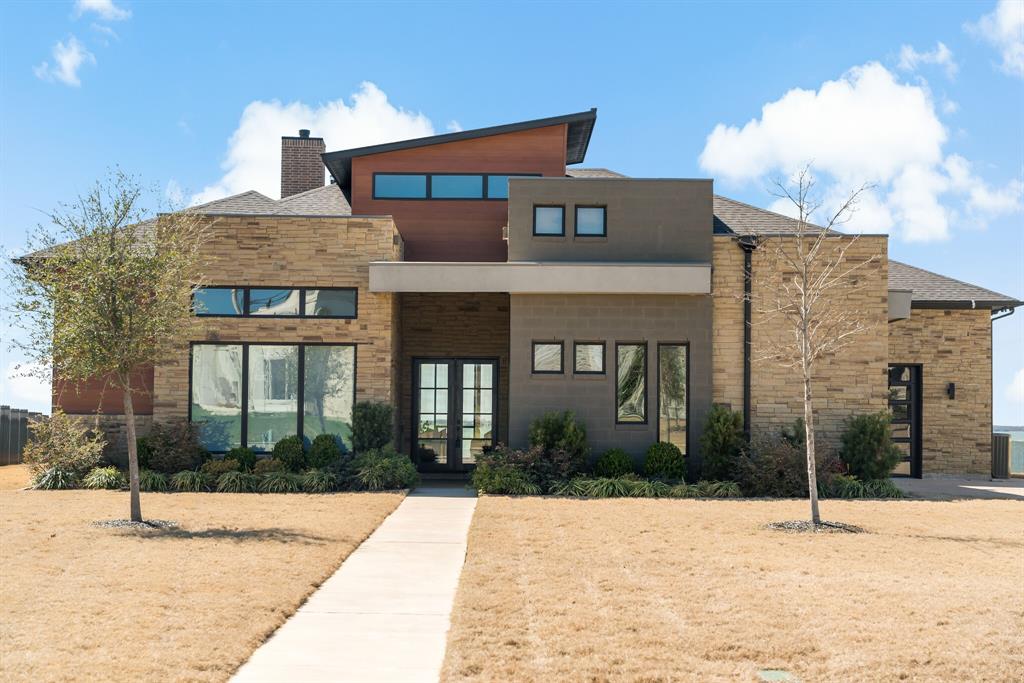 An exquisite lakefront property in the prestigious Heath Golf and Yacht Club. This magnificent home, built in 2020, is nestled on over a half-acre and offers breathtaking lake views at every turn. As you step inside, you're greeted by stunning water views and a contemporary design with 4 bedrooms and 4.5 bathrooms. The home features soaring ceilings and full-wall windows, providing panoramic views of the outdoors. The spacious great room boasts a sleek linear fireplace, while the chef's kitchen is a culinary masterpiece with elegant white and gray granite and a huge waterfall island for both cooking and entertaining. The primary bathroom offers a spa-like experience with a double-head shower, a copper-adorned standalone tub, and an expansive walk-in closet. Each bedroom is equipped with an ensuite bath. The 3-car garage provides ample space for vehicles, a golf cart, and additional storage. Step outside to the covered outdoor living area with a fireplace, ideal for entertaining or simply relaxing while taking in the tranquil lake and sunset views. Don't miss the opportunity to own this exceptional lakeside retreat that defines luxury and comfort.