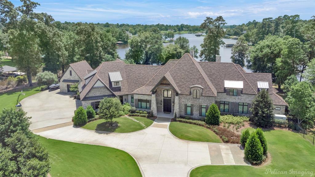 An Unrivaled Lakefront Paradise with 6,777 SF Estate on 3.6 Private Acres. Escape to ultimate privacy and luxury on the shores of Woodlake Ridge. Nestled on 3.6 acres with an astounding 900 feet of pristine lake frontage, this custom built masterpiece is a definitive statement in lakefront living. Spanning 6,777 square feet, the residence seamlessly blends modern architectural design with the timeless warmth of rustic charm. From the moment you enter, the craftsmanship is evident. The interior is defined by Grand Living Spaces, featuring soaring vaulted ceilings anchored by stunning reclaimed exposed wood beams. The Natural Beauty of Unstained natural hardwood floors flow throughout, creating a bright and inviting atmosphere that complements the surrounding landscape.  At 6,777 square feet, this home is thoughtfully designed to cater to large families and grand-scale entertaining while maintaining a sense of intimate home comfort. The rear of the property is a true sanctuary designed to maximize the breathtaking lake views. Starting with an expansive covered patio area that is a perfect setting for sunset dinners, complete with a professional grilling area. Take a refreshing dip in the sparkling pool or enjoy a relaxing soak in the private resort-style hot tub, all while overlooking the tranquil waters of the lake. The 3.6 acre lot ensures total seclusion, creating a private park-like setting rarely found in lakefront subdivisions. The Premier boathouse & waterfront area are perfect for the water enthusiasts, the private boathouse has functionality with dedicated slips for a fishing boat, a ski boat, and two jet skis. A deck area perfect for lounging or jumping into the water along with a designated area designed for cleaning your day's catch right at the water's edge. This is a once-in-a-lifetime opportunity to own this premier luxury home in Woodlake Ridge. Experience the perfect harmony of luxury, nature, and recreation. Schedule your private tour today!