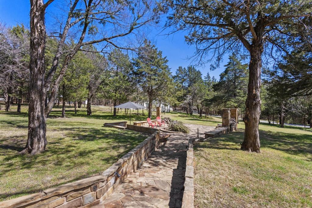This TURNKEY Lake Texoma resort style STONE RETREAT provides you a large SHOP for parking your RV indoors.  Designing WELLNESS was the decorator's goal in styling this rustic, one-of-a-kind lake property with high-end furnishings.  Look far and wide...you will be challenged to find another property as special as 236 Homesite.  Sited on 1.24 manicured acres with gated entry, with many activities available to guests;  flagstone walkway leads to large flagstone firepit, relax in your outdoor hot tub perfectly located in a screened area, expansive wraparound deck, shed, outdoor shower, extra spacious, 1470 sq ft, boat and RV storage with room for lake toys, multiple outdoor entertainment areas for swinging, playing horseshoes or cornhole, grilling, and more.  The interior features a woodburning fireplace with live-edge mantle, chef's kitchen with 4-burner gas range with griddle, stainless steel dishwasher and appliances, quality wood and stone floors throughout, a large bunkroom with 4 bunks, primary suite with spa en-suite bath, laundry area, separate TV or gaming area with spacious table for board games or dining.  Wow!  This is the one! 2025 is the YEAR to find YOURSELF!