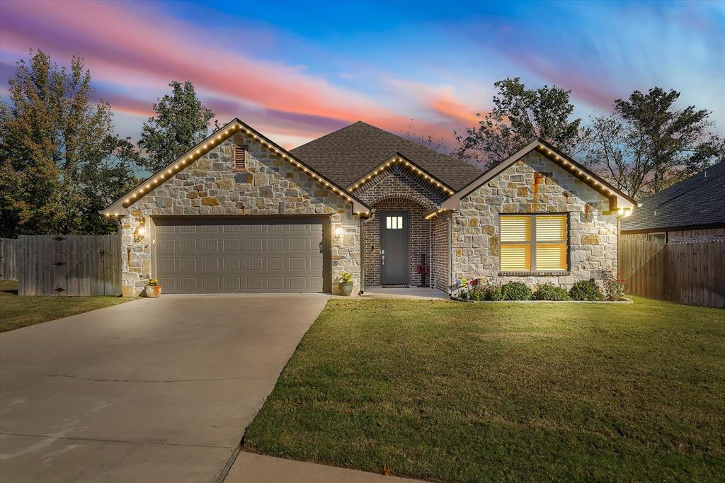 Move-in ready and beautifully finished, this home stands out in one of Flint’s favorite neighborhoods. The moment you walk in, you’ll notice the bright, open layout, tall ceilings, crown molding, and warm natural light. The living room features a cozy fireplace and flows seamlessly into a stunning kitchen with upgraded countertops, large island, gas range, custom-style cabinetry, and beautiful lighting. This kitchen truly sets the home apart from others in the area and gives it that elevated, custom feel. The primary suite is spacious and private with a well-appointed bathroom and great closet space, while the guest rooms are comfortable and tucked away for easy everyday living. Out back, you have a covered patio with ceiling fans and just enough yard to enjoy without spending your weekends maintaining it. Additional features include outdoor Jellyfish lighting, a full brick and stone exterior, wood-look flooring, upgraded fixtures and finishes throughout, and a two-car garage. Conveniently located near schools, dining, and Lake Palestine, this home is the perfect blend of comfort, style, and low-maintenance living.