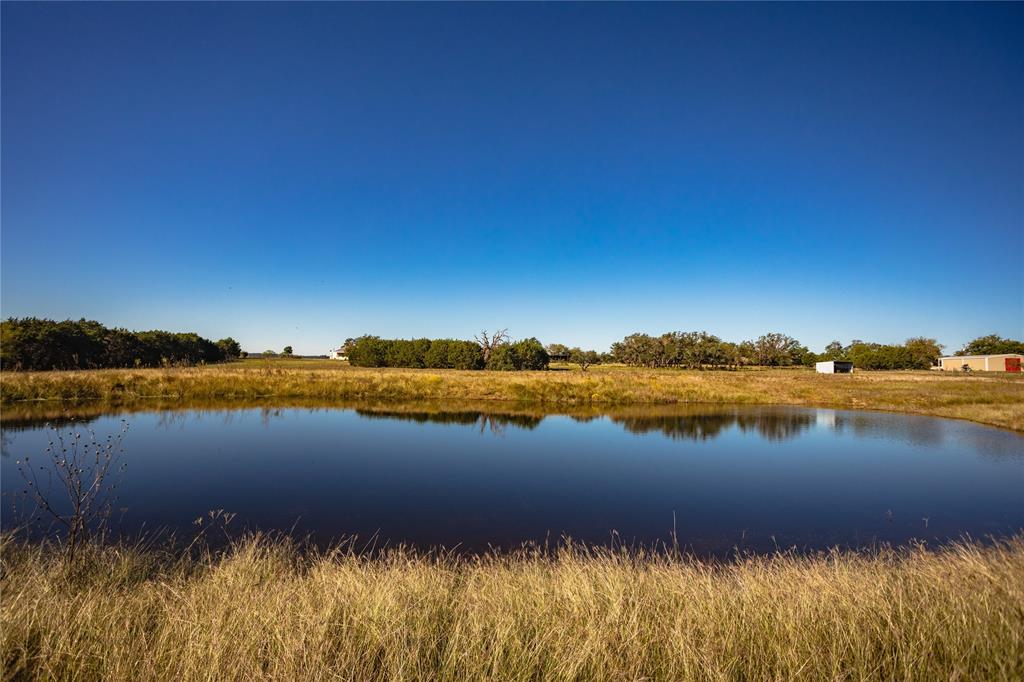 16 acres north of Meridian with barndominium, shop, barn, pond, and views, all on ag exempt land. Open concept living, kitchen, dining with 2 bedrooms, 2 baths, separate laundry, and large bonus room adaptable as den, living area, bedroom, or office.  Master bath has claw foot tub and separate shower.  Home has concrete floors, plantation shutters, custom cabinets, cedar closet, lots of cabinets, wheelchair accessible doorways. Well maintained home with big deck on the front, metal roof overhang on three sides, carport for 3 vehicles. Large barn with shop and equipment bays. Carport doubles as patio with propane jet for outside grilling.  Land is gently rolling, with views to the south and southwest. Nice pond that still has water. The property is fenced and cross fenced for goats, sheep or other livestock. Original farmhouse surrounded by trees remains on the property.  Water supplied by private well.  Gated entrance on quiet county road with nice neighbors.  Located on paved road.