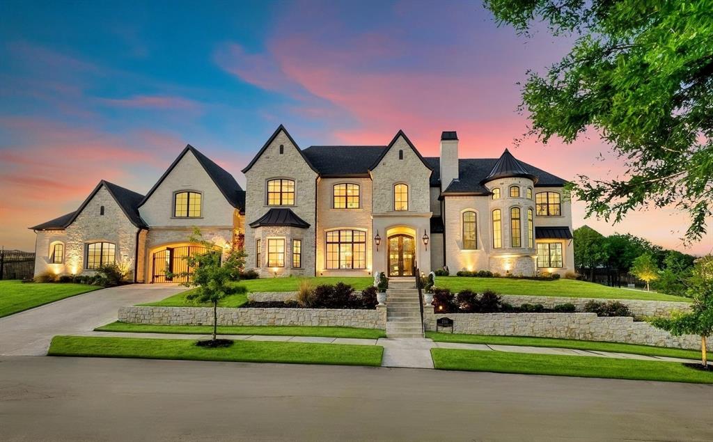 Nestled beyond the guarded gates of Castle Hills’ most exclusive enclave, Enchanted Hill, 2310 Silver Table Drive is a striking architectural masterpiece redefining luxury in the heart of DFW. Completed in 2020 with exceptional attention to detail, this immaculate estate offers nearly 6,600 ft. of refined living, designed for both grand entertaining and everyday elegance. Perfectly positioned on a premium half-acre corner lot, the home captures breathtaking hilltop views. Inside, soaring 23-foot ceilings, a sweeping staircase, and walls of windows create a dramatic yet inviting atmosphere where brilliant natural light flows throughout. The home features five spacious bedroom suites, each with a private bath, along with three additional powder baths, a stately wood-paneled library, formal dining, game and card rooms, and a private exercise studio. The chef’s kitchen is equipped with Wolf and Sub-Zero appliances, complemented by a full caterer’s prep kitchen. Additional highlights include a 185-bottle wine cellar, dual wet bars, reverse osmosis with whole-home water filtration system, elevator, two staircases, and four fireplaces. The primary suite is a private retreat featuring dual custom closets, a coffee bar, and a spa-inspired bath with an oversized walk-in shower, foot claw cast iron tub, dual vanities, and separate commodes. A state-of-the-art theater room offers a 133-inch screen, 7.1 surround sound, and wet bar. Outdoors, enjoy a resort-style setting with a covered patio, outdoor kitchen, fireplace, and a 24,000-gallon pool & spa with fire and water features. An oversized four-car garage completes the home. Residents enjoy 25+ parks, pools, sports facilities, and access to a top-ranked private golf course, all near Legacy West, The Star with convenient access to DFW Airport, Highway 121, and I-35, Castle Hills seamlessly blends suburban tranquility with urban convenience. This is more than a home, it is a statement of elevated living.