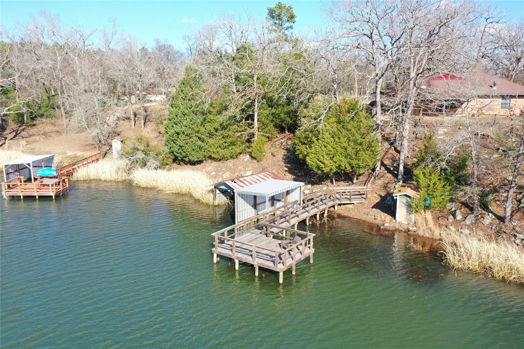 Don't Pack, Just Get Here!! Everything is included--Furniture, Appliances, Bedding, Linens, & Dishes. Incredible views from this one of kind lakehouse on top of a rocky hill. Burleson Lake is a 44 acre private lake, hiking trails, & hunting area on approx 249.91 shared acres. Consisting of just 60 shares, one share lot equals 150 ft deep x 150 ft lake frontage with the balance of the 4.2 acres owned jointly. Spacious floor plan, galley kitchen and sitting area with large windows for admiring the -to die for- views. 4 bedrooms & 2 baths provide a comfortable place for you & your guests. Primary bedroom with ensuite bath that also has access from the hallway, tub & shower combo, & dual sink vanity. Bedroom 2 with ensuite bath, Bedrooms 3 & 4 are on the opposite side of the home. Large laundry rm, Covered back porch with gated access to steps for added safety. Pier built in the last 5 years. Approx midway betwn Houston & Dallas, approx 75 miles east of Waco.