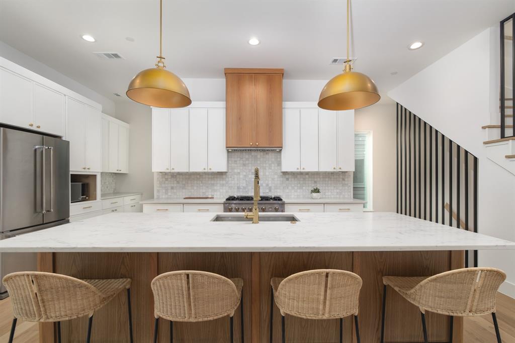 Crafted by the renowned Strange and Sons Development, Cedar Springs Townhomes delivers twenty one modern residences in the heart of Dallas. Interiors are bright and refined, planned for natural light and easy flow. The main level centers on a chef kitchen with white cabinetry, warm wood accents, brass hardware, and Calacatta style quartz on a generous island with an under mount sink. A marble backsplash, brass dome pendants, and a premium stainless package with a six burner gas range, hood, French door refrigerator, built in microwave, and dishwasher complete the space. The great room brings wide plank oak floors, a window seat, and sliders to a private balcony. Upstairs, a spa bath offers dual quartz vanities, oval mirrors, globe lighting, and brushed brass fixtures. The wet room is enclosed in frameless glass and places a freestanding soaking tub inside the shower for a true retreat, with walk in storage nearby. Many plans add a flexible loft for media, office, or guests, with floating shelves and a compact cabinet bar. Outdoor living shines with covered and open balconies, and select homes provide expansive rooftop terraces with a shaded pergola and city views. Architecture is clean and contemporary with strong curb appeal. From this central address you are close to Oak Lawn and Uptown dining and nightlife, the Katy Trail and Turtle Creek Park, West Village, Downtown, the Medical District, the Dallas North Tollway, and Dallas Love Field. Cedar Springs Townhomes pairs elevated finishes, flexible spaces, and a walkable location, with the craftsmanship of Strange and Sons Development.