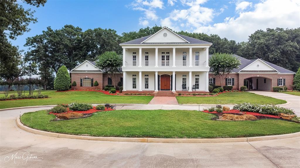STUNNING, ONE OF A KIND, Plantation Style Home with balcony views of landscaped grounds & breathtaking sunrises! All trim, cabinets, and hardwood floors custom made from trees on owners' family land! Surrounded by 13.7 acres of manicured property.   Primary BR has a fireplace and 2 HUGE walk-in closets plus a spacious bath with separate vanities, 2 toilet rooms, jetted tub, separate shower. Living Room, Dining Room, Front Entry, and bedrooms have custom made oak hardwood floors.  More awesome features of this home are: Fire sprinkler system, 2 water wells, beautiful landscaping, 8 acres of irrigated sod, 75 KW generator, geothermal heat pump HVAC system, remote controlled entry gate, Mosquito Mist, Starlink internet or fiber optic cable.  Separate Barndominium with bedroom, bath, kitchenette, and a 24 x 36 room. Includes 48 x 80 Barn that has 656 SF unfinished apartment upstairs. Bring your horses or cattle!