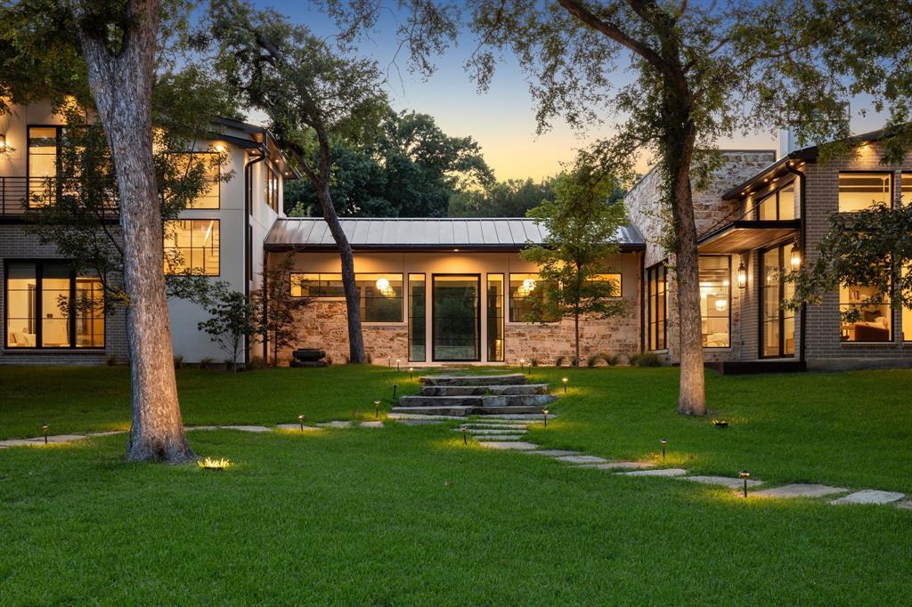 Welcome to 13919 Hughes Lane located in the prestigious Preston Road North Estates neighborhood of Dallas. Positioned near Northwood Club and within close proximity to Dallas’ most sought-after private schools, this estate delivers a rare sense of privacy, connection to nature, and exceptional craftsmanship. From the moment you arrive, it’s clear this is not just a home, but more of a zen retreat that was designed to be experienced, enjoyed, and remembered. Featuring 4 bedrooms and 4.5 bathrooms on the main level, and offering 5,190 square feet of living space set on a truly rare 1.18ac lot. The home features premium materials that harmonize with the natural beauty of its surroundings. The exterior, interior, & pool area are adorned with cave-rock and limestone sourced locally from Austin. Wall-to-wall collapsible doors open the living spaces to the serene outdoor spaces, creating a true indoor-outdoor living experience. Natural limestone floors flow throughout the first floor and around the pool, accented by handmade Moroccan Zellige tiles. The kitchen boasts imported natural quartzite countertops, Wolf appliances, and designer finishes. All bathrooms are equipped with Rohl faucets and Toto fixtures, and the home is adorned with high-quality imported window treatments and exquisite lighting fixtures throughout. Use your imagination with the tree top retreat on the 2nd floor, which can be used as an office, living area, studio, or library. The resort-style pool blends seamlessly with the home, with limestone floors extending from indoors to outdoors. An outdoor kitchen, equipped with Wolf appliances, is perfect for gathering. The grounds showcase 40+ mature trees, 1,170 SF of patio area, imported garden accents, and a private gazebo—an ideal setting for enjoying nature and the abundant wildlife. 13919 Hughes is a rare offering where scale, setting, and craftsmanship come together—presenting a truly unique opportunity to own one of the area’s most exquisite estates.