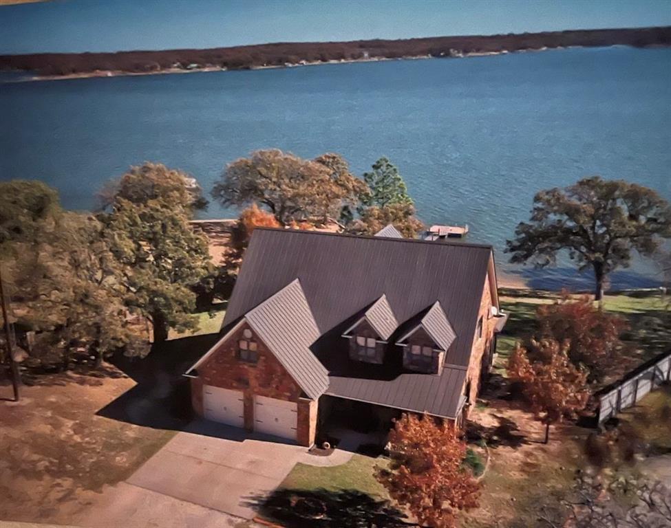 Open the door to a relaxed landing coupled with immediate views of the lake. This lush 3–4-bedroom 2.5 bath retreat is a desired inner depth locale on Lake Nocona main body waterfront. From the transparent living area with a floor to ceiling stacked rock gas fireplace with electric thermostat that dominates the entire room for personal comfort to the enhanced functionality of the hefty kitchen island with under storage that ties all the essentials together including built in gas burners, microwave, & desired double ovens, this kitchen is equipped. Oversupply of cabinets with endless granite countertops to assure all clutter is contained. Mass area for a large dining table with vintage views that never go out of style. Well placed windows that flood the rooms with natural light that gives an indoor-outdoor feel. Half bath for guests. Large utility with counter for good working space. Main bedroom is conveniently located downstairs for long term use with tranquil lake views for a bright start to the day & a peaceful close in the evenings. Designer like closet with window. Dual sinks, separate shower, & a sunken garden tub. Upper level offers 2 bedrooms & full bath with room-to-room harmony that's adjoined by the clever catwalk with wrought iron detail & captures the attraction of the centerstage below. No upstairs is complete without a bonus entertainment room & if the need for additional beds is a must install barrack style bunk beds for a cozy fix. Work from home with a fully implemented office. Outdoor boasts a waterfront shaded gathering space that makes the perfect backdrop for entertaining or absolute relaxation. Covered patio on the lakeside. Nothing like sitting on the porch with a lake vibe watching all the action. Rock Retaining wall. Large 2 garage & plumbed for water & ice maker. 3 HVAC units. If you've been on the sidelines now's the time to nudge those decisions & follow the roadmap. This one's up for grabs! Survey shows property to be 0.8339