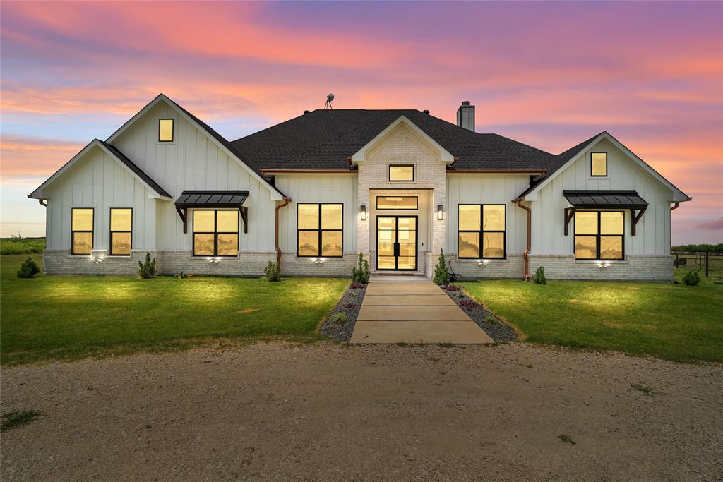 Experience refined country living on 17 beautifully manicured acres in Ennis Texas. This 2023 custom-built 4-bedroom, 3-bathroom estate blends timeless craftsmanship with modern luxury, offering privacy, quality, and exceptional attention to detail throughout.

From the moment you arrive, the home's striking curb appeal makes an unforgettable impression with oversized custom windows and doors, Juliet-style metal awnings accented by handcrafted cedar brackets, and an impressive wrought iron front entry door. Inside, wide-plank white oak hardwood flooring flows seamlessly through the foyer, office, living room, kitchen, and dining area, creating a warm and sophisticated atmosphere.

Designed for both everyday living and entertaining, the gourmet kitchen features 12-foot custom white oak cabinetry, stunning Carrara marble countertops and full-height backsplash, premium stainless steel appliances, an oversized island with seating, and abundant storage. The spacious living area is anchored by a beautiful stone fireplace and opens effortlessly to the covered outdoor living space.

The dedicated home office is a standout feature, complete with floor-to-ceiling custom built-ins and a tray ceiling, creating an ideal work-from-home environment. The private owner's suite also features a tray ceiling and a luxurious spa-inspired bath with an oversized walk-in shower, freestanding soaking tub, dual vanities, and generous walk-in closets.

Step outside to enjoy peaceful Texas sunsets from the covered patio featuring a wood-planked vaulted ceiling and outdoor fireplace. The fully fenced acreage includes a stocked pond, mature trees, open pasture, and plenty of room for horses, livestock, recreational activities, or future improvements.

Offering the perfect balance of luxury, privacy, and country living while remaining just minutes from Ennis and convenient access to the Metroplex, this exceptional property is a rare opportunity to own a truly one-of-a-kind Texas estate.