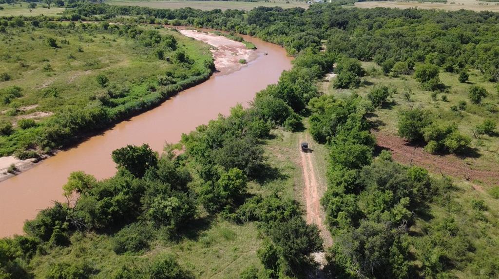JYN RANCH – 250 Acres of Scenic Beauty & Functionality. Welcome to your private 250 acre retreat with approximately 1.6 miles of Brazos River frontage. This exceptional property offers a perfect balance of recreation, ranching, and comfortable living two hours from DFW metroplex and 30 minutes from Graham for a quick trip for dinner.  Situated on the ranch is a fantastic 4,000 sq.ft. barndominium featuring 1,687 sq.ft. of beautifully finished living space.  With 3 bedrooms, 2 full bathrooms, stained concrete floors, and a warm rustic interior, it’s ideal for full-time living or weekend escapes. The open-concept layout centers around a well-appointed kitchen, perfect for entertaining and opens to a spacious wrap-around porch, offering peaceful views and outdoor relaxation. Attached is a 2,313 sq.ft. insulated shop with 5 overhead doors, one with electric opener, providing ample space for equipment, storage, and projects. Living space, shop, wrap around porch and shed under roof is 6,500 s.f.  An EF-5 rated storm shelter located in the shop. The ranch is fully serviced with co-op water and electricity, with two water meters and one electric meter.  On the ranch is also a well-maintained 3 bed, 2 bath double-wide that offers comfortable accommodations for guests or extended family. It features a covered porch and a cozy fire pit area, perfect for gatherings under the stars. The land is fully fenced and cross-fenced, with pens and chutes for livestock. Approximately 65 acres of cultivated ground are being converted to improved grasses, enhancing its agricultural value. The balance of the property is heavily wooded with mature oaks, two stock tanks, and sandy loam soil, creating a haven for wildlife, hunting, and fishing. Capability of creating a waterfowl detention area for hunting with the tanks.   This is more than a property—IT'S A LIFESTYLE.  Whether you're looking for a recreational paradise, a working ranch, or a peaceful riverfront escape, this ranch has it all.