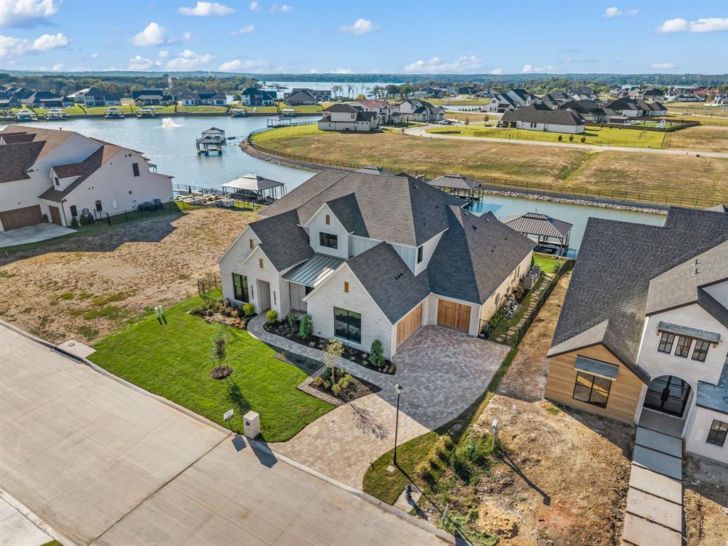 Experience lakeside living at its finest in this exquisite custom home nestled on the shores of Eagle Mountain Lake. Boasting 5 spacious bedrooms, 4.5 designer bathrooms, and a 3-car garage, this home offers an ideal blend of elegance, comfort, and functionality.

Step into an expansive open-concept great room, kitchen, and dining area, perfectly designed for entertaining. The chef-inspired kitchen features an upgraded appliance package including a 48” 6-burner gas cooktop, double wall ovens, and a built-in refrigerator. Custom cabinetry throughout the home is enhanced by soft-close drawers, floating shelves, and under-cabinet toe-kick lighting, adding both style and convenience.

The white oak wood flooring flows seamlessly through all living spaces and into the luxurious primary suite. Step outside to a massive covered patio overlooking your private pool and breathtaking lake views—an ideal space for relaxing or hosting guests.

Upstairs, enjoy a spacious game room complete with a wet bar and access to an upper-level balcony that also captures serene pool and lake vistas.

With too many high-end features to list, this home is truly a must-see. Schedule your private tour today and discover the ultimate in luxury lake living.