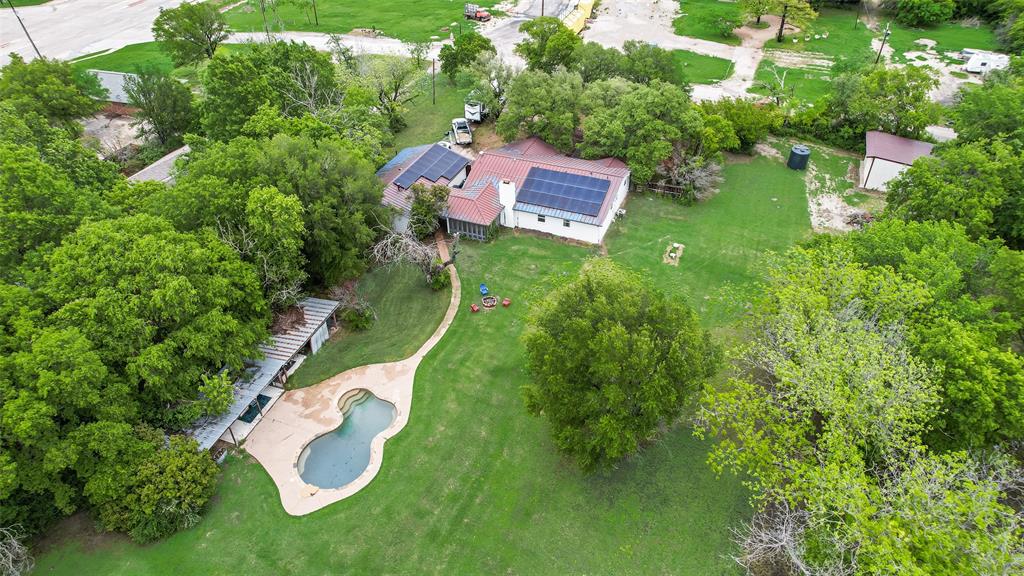 This cozy farmhouse offers tons of space with large lot, privacy, and endless possibilities with no HOA or restrictions. The backyard is private and features a pebble-finish large pool, deck, and metal storage cabana, great for entertaining. 26x32 foot metal building on a cement slab and 14’ ceilings, perfect for storage, equipment, or a auto workshop. Inside, the home features an open galley kitchen with new soft-close cabinets, granite countertops, and a 5-burner gas stove. A cozy breakfast room sits off the kitchen, with a formal dining room on the other side for easy flow. The spacious primary bedroom offers a sitting area and multiple closets. The living room showcases a classic wood-burning fireplace that efficiently heats the home. There is also an oversized garage connected to an 11x24 workshop or man cave. There is room in front living for 3rd bedroom or the room across walkway from kitchen would make great mother-in-law suite. Plenty of room to park RVs, boats, or multiple vehicles for a business. Additional upgrades include a premium metal roof (insurance-friendly), new electric panel, large water storage tank, and freshly painted white exterior brick. A brand-new high-end solar system with a lithium battery and upgraded panel will keep your electric bills low. With no HOA, this property offers rare freedom to expand or build additional structures.