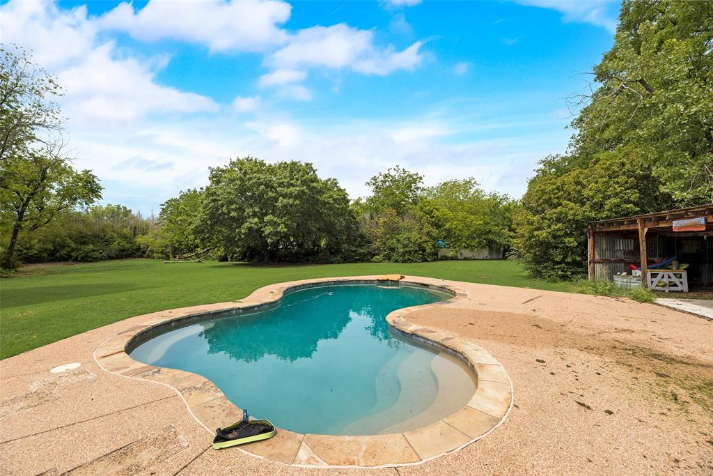 This cozy farmhouse offers tons of space with large lot, privacy, and endless possibilities with no HOA or restrictions. The backyard is private and features a pebble-finish large pool, deck, and metal storage cabana, great for entertaining. 26x32 foot metal building on a cement slab and 14’ ceilings, perfect for storage, equipment, or a auto workshop. Inside, the home features an open galley kitchen with new soft-close cabinets, granite countertops, and a 5-burner gas stove. A cozy breakfast room sits off the kitchen, with a formal dining room on the other side for easy flow. The spacious primary bedroom offers a sitting area and multiple closets. The living room showcases a classic wood-burning fireplace that efficiently heats the home. There is also an oversized garage connected to an 11x24 workshop or man cave. There is room in front living for 3rd bedroom or the room across walkway from kitchen would make great mother-in-law suite. Plenty of room to park RVs, boats, or multiple vehicles for a business. Additional upgrades include a premium metal roof (insurance-friendly), new electric panel, large water storage tank, and freshly painted white exterior brick. A brand-new high-end solar system with a lithium battery and upgraded panel will keep your electric bills low. With no HOA, this property offers rare freedom to expand or build additional structures.