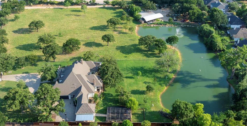 Discover a truly one-of-a-kind property in Denton County, set on 6.5 scenic acres and featuring a stunning 1-acre pond with a lighted fountain. The current agricultural exemption—despite today’s 10-acre minimum—can be transferred to the new owner, offering significant tax savings. With no HOA, you’ll enjoy maximum flexibility in how you use the property.  This custom-built home offers over 5,700 square feet of living space with a thoughtfully designed, versatile floor plan ideal for a variety of lifestyles, including multigenerational living. Upstairs, you’ll find expansive flex space perfect for an art studio, music room, homeschooling, exercise room or even climate-controlled storage.  The home is loaded with premium features designed for comfort and functionality.  The gourmet kitchen boasts commercial-grade Thermador appliances, a large island with a vegetable sink and ample counter space—perfect for everything from daily meals to large-scale entertaining.  The massive walk-in pantry provides abundant storage for food, beverages, and both everyday and seasonal dishware.  Outdoor living is just as impressive, with a built-in grill, stone fireplace, and sink, plus multiple access points to patios where you can enjoy serene pond views, lush landscaping, and breathtaking sunsets.  For hobbyists and outdoor enthusiasts, the property includes a 30' x 60' greenhouse equipped with hose bibs connected to both pond and city water. There’s also a spacious workshop featuring a 100-amp breaker (including 220V outlet for a welder), plumbing, natural gas, a standing air compressor, and a fully equipped separate living space complete with heating, air conditioning, kitchen appliances and washer & dryer.  Need space for vehicles or recreational equipment? This property delivers with a 5-car garage, ample additional parking, and a large covered RV area with 50-amp service.  Too many other amenities to list!  $600,000+ UNDER APPRAISED VALUE...Owner financing is available.