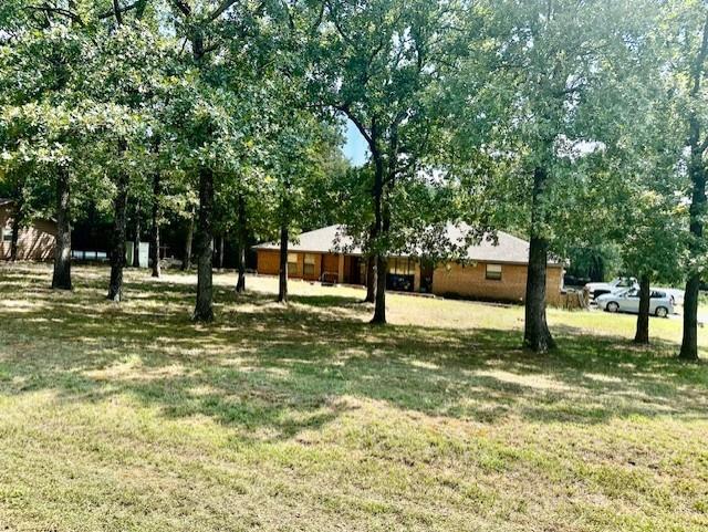 NO CITY TAXES & NO HOA! Escape to this rare, 2.14-acre country home, in Cross Timbers Estates, just east of Denison, Tx, off Hwy 69.  Positioned on a spacious corner lot with mature shade trees, this 1985 home is perfect for small acreage living. Step out onto the massive, covered back deck to experience total serenity—the home’s layout helps to add privacy from the street and side neighbors, leaving you with peaceful views of your backyard and the remainder of the 2.14 acres. Inside, enjoy a move in ready,  3, possibly 4 bedroom, 2.5-bathroom floor plan featuring fresh interior paint, modernized lighting, an attached garage, and a cozy wood fireplace. This property has a detached workshop with a concrete floor, electricity, and possibly water—plus a separate covered RV parking bay and an additional storage unit. Perfect for hobbyists, contractors, or Lake Texoma boat owners looking for freedom from city restrictions and high storage fees. Properties offering this blend of acreage, utility, and monthly tax savings since outside the city limits are incredibly rare at this price point. Schedule your tour today and experience the privacy for yourself! All information deemed correct and accurate, however buyer and buyer’s agent to verify all information.