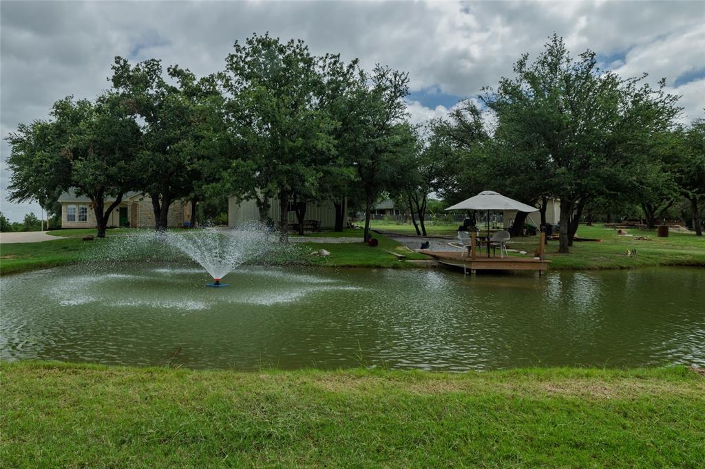 Welcome to your own private retreat in Runaway Bay! Situated on a beautiful 1-acre lot, this well-maintained 3-bedroom, 2-bath home offers 1,733 square feet of comfortable living space and the perfect blend of peaceful country living with modern conveniences. Step outside and discover a backyard designed for relaxation and entertaining. Enjoy evenings around the propane fire pit while taking in the breathtaking Texas sunsets, or host family and friends in a setting surrounded by mature oak trees and picturesque views. A small stocked pond complete with a fountain and private dock provides a tranquil focal point and is perfect for fishing catfish right in your own backyard. For those needing extra space, the 25' x 30' shop offers plenty of room for hobbies, storage, or projects. Garden enthusiasts will appreciate the fenced garden area, while the expansive acre provides room to roam and enjoy the outdoors. Two separate concrete driveways offer added convenience and ample parking for guests, trailers, boats, or recreational vehicles. Inside, you'll find a spacious and inviting layout featuring three bedrooms and two full baths designed for comfortable everyday living. Whether you're looking for a place to entertain, enjoy peaceful evenings under the stars, or simply escape the hustle and bustle, this property delivers the ideal Texas lifestyle. Conveniently located in Runaway Bay and just minutes from Lake Bridgeport, golf, dining, and everyday amenities, this unique property offers the space, privacy, and outdoor features you've been searching for. Don't miss the opportunity to make this one-of-a-kind property your next home!