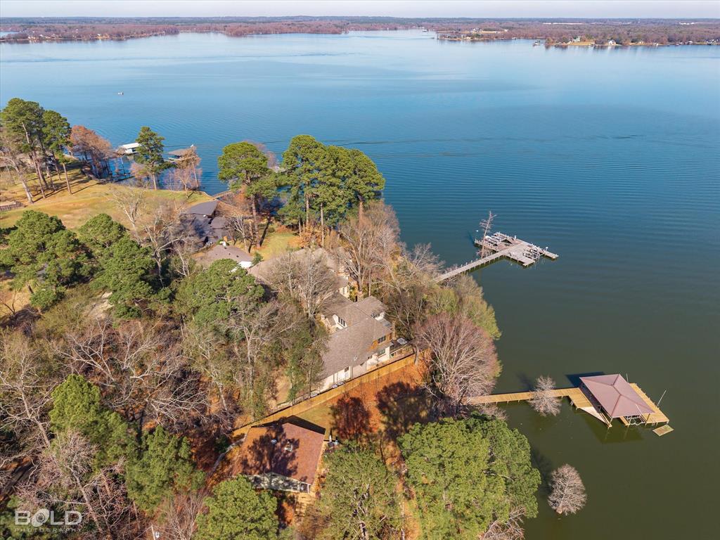 One-of-a-kind architect-designed waterfront estate on a stunning 1.38-acre peninsula lot with some of the longest unobstructed views on Cross Lake. Private gated cut-de-sac with just two homes, protected by Covenants, wooded buffer for added privacy. Custom-built single-owner home with 3,380 heated sq ft and extraordinary craftsmanship including antique reclaimed wood from a historic Shreveport warehouse, solid-core doors, Adirondack Naturals doors, insulated, metal-clad wood windows by Vetter and 10 ft ceilings with a soaring 17 ft 4 in vaulted Great Room. East-facing orientation provides breathtaking sunrises and moonrises, natural shade in the afternoons, cooling south and east breezes and exceptional storm protection. Outdoor living includes a two-level deck with a functional hot tub, screened porch with built-in vent hood and space for grilling, flagstone firepit with 180 degree open-water views and a 125 ft engineered pier with two 3,000 lb boat lifts, jet ski lift, docking for a 24 ft party barge, water access, underground drainage and utilities in place for a future boathouse. The chef’s kitchen features black granite countertops, all pull-out cabinetry, multiple appliance garages, Sub-Zero and Dacor appliances including convection oven, 50 lb ice maker, excellent pull-out vent hood, trash compactor, walk-in pantry and lake views. The primary suite includes a two-person shower, walk-through closet to laundry and built-in ironing board.  The home includes a post-tension slab, heavy-duty Z-wall retaining system with French drains, future elevator shaft, oversized garage with storage rooms, whole-home generator, bug misting system, thick exterior walls for high efficiency, underground drainage to the pier and lake-fed irrigation. A rare opportunity to own a master-crafted estate with unmatched privacy, water frontage and panoramic lake views. Please see the list of features and more information attached.
