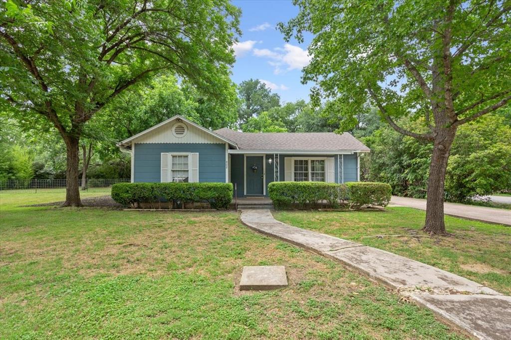 Tucked beneath two towering pecan trees on a generous .4-acre corner lot, this 1950 blue cottage sits just a short stroll from Magnolia Gristmill in the heart of Valley Mills. The covered front porch was made for slow mornings, and the oversized yard offers the kind of space that's nearly impossible to find this close to town.
Inside, 2 beds and 1 bath are wrapped in warm wood paneling and refinished floors. The kitchen is bright and functional with soft blue cabinetry, and each bedroom carries its own personality — one with a sculptural accent wall, the other dressed in reclaimed wood.
Out back, a covered patio strung with bistro lights overlooks a private, tree-shaded yard complete with a turf putting green, storage shed, and detached garage. There's room here to garden, entertain, or expand.
Properties like this rarely come to market in Valley Mills. Original 1950s character, solid bones, and a coveted corner lot in one of the most walkable pockets in town — a rare opportunity for investors, flippers, or visionary buyers ready to bring their tool belt and their imagination.