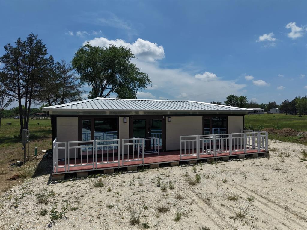 This brand-new 3-bedroom, 1-bathroom modular home at 1316 East Titus Street delivers 800 square feet of modern living on 0.83 acres in Mexia, Texas. The home features an open-concept layout with luxury vinyl plank flooring, a modern kitchen with dark countertops and white cabinetry, a glass walk-in shower, and a large full-width covered front deck perfect for outdoor living. A smart keypad door lock provides keyless, code-based entry, and floor-to-ceiling windows and sliding glass doors flood every room with natural light and open rural views. City utilities are connected and active. The property sits on level land in the Elm Creek Residences Subdivision with no POA or HOA fees and is not in a FEMA flood zone. Three bedrooms give buyers flexibility that a 2BR simply can’t match whether for family, guests, or a home office. Located under an hour from Waco and roughly 90 miles from Dallas, this is one of the most accessible new construction opportunities in Limestone County.