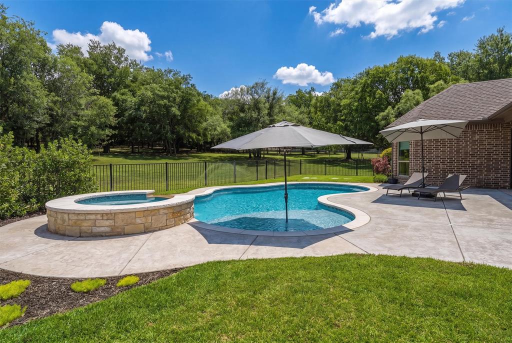 Sellers now offering a $15,000 BUYER BONUS for an executed contract by July 1st! Custom-built in 2017 and located in the highly sought-after Estancia community, this rare single-story home offers approximately 3,239 sq ft on a private 1.5-acre cul-de-sac lot surrounded by mature trees. Homes in this neighborhood rarely come available, and single-story properties are especially hard to find.
This 4-bedroom, 3.5-bath home features a dedicated office, formal dining room with tray ceiling, hand-scraped hardwood floors, and an open-concept layout designed for both everyday living and entertaining. The kitchen offers upgraded quartz countertops, soft-close cabinetry, gas cooktop with pot filler, double ovens, glass-front upper cabinets, abundant storage, and a coffee & wine bar connecting the dining area.
The spacious living room showcases a coffered ceiling, stone gas-start fireplace, and in-ceiling speakers. The oversized primary suite includes tray ceilings and a spa-inspired bath with dual shower heads, extended soaking tub, upgraded quartz countertops, and direct access to the laundry room with additional cabinetry, counter space, and full-size refrigerator.
Outdoor living features a saltwater pool & spa installed in 2023, fire pit, covered patio with tongue-and-groove ceiling, in-ceiling speakers, Christmas light outlets, and a 16-zone sprinkler system. Additional features include a 3-car garage, two AC units, water softener, security system, well water with no water bill, and new carpet in select rooms (2025).