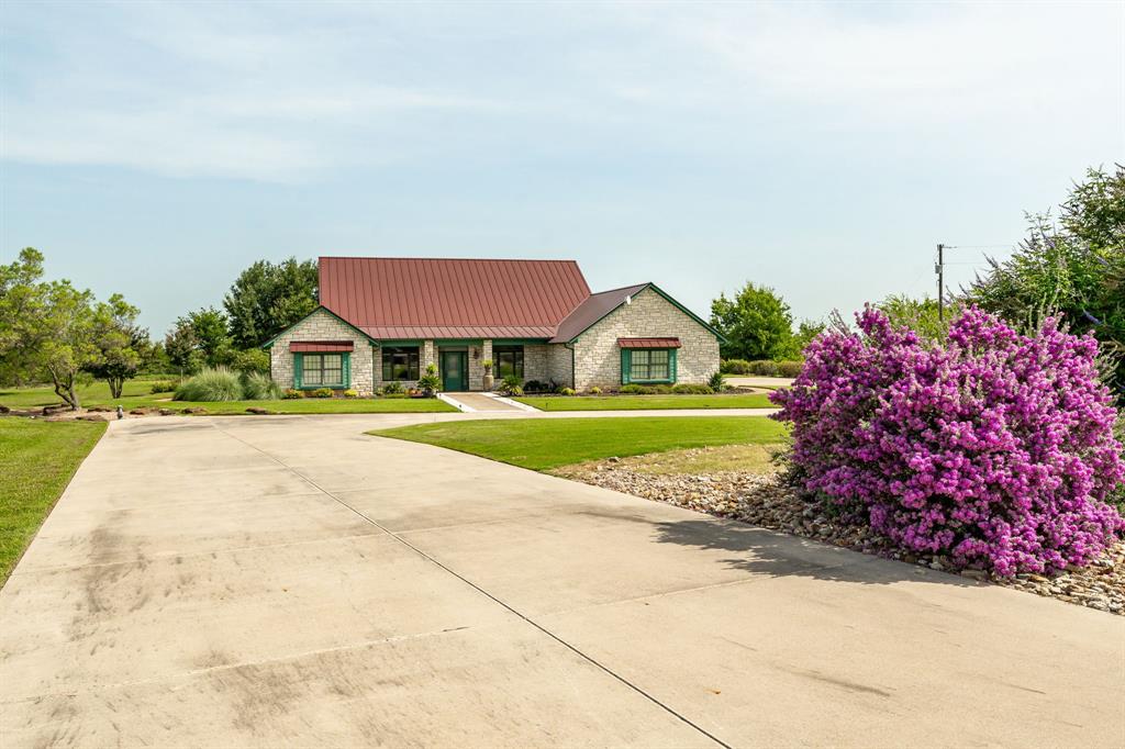 Seldom does the the opportunity to own a custom home of this caliber come along! This home on approximately 2.5 acres in Comanche County offers both privacy and beautiful views.  Built in 2006, this 3,011 square foot residence sits on a hilltop, providing amazing views across the surrounding countryside and a sense of seclusion while maintaining convenient access to town and area amenities.
The home includes three bedrooms, two full bathrooms, and one half bath. The primary suite features an ensuite bathroom and a large walk-in closet. Secondary bedrooms are connected by a Jack-and-Jill bathroom, offering flexibility and efficiency for family or guests.
Interior highlights include a spacious, well-appointed kitchen with granite countertops, abundant cabinetry, and an open layout. Real Brazilian cherry hardwood floors add warmth and character throughout much of the home. The floor plan is designed for both comfortable daily living and entertaining.
Property features an Austin stone exterior and a standing seam metal roof, providing durable, low-maintenance construction. The manicured and irrigated yard showcases established landscaping and creates a beautiful setting for outdoor enjoyment. A large covered patio offers an ideal space to relax, entertain, and take full advantage of the views.

Properties offering this combination of acreage, hilltop views, quality construction, established landscaping, and proximity to town are rarely available. This property represents a unique opportunity for buyers seeking a well-built home, scenic setting, and long-term value in a rural location.

Don't let this one get away, it is truly one of a kind!