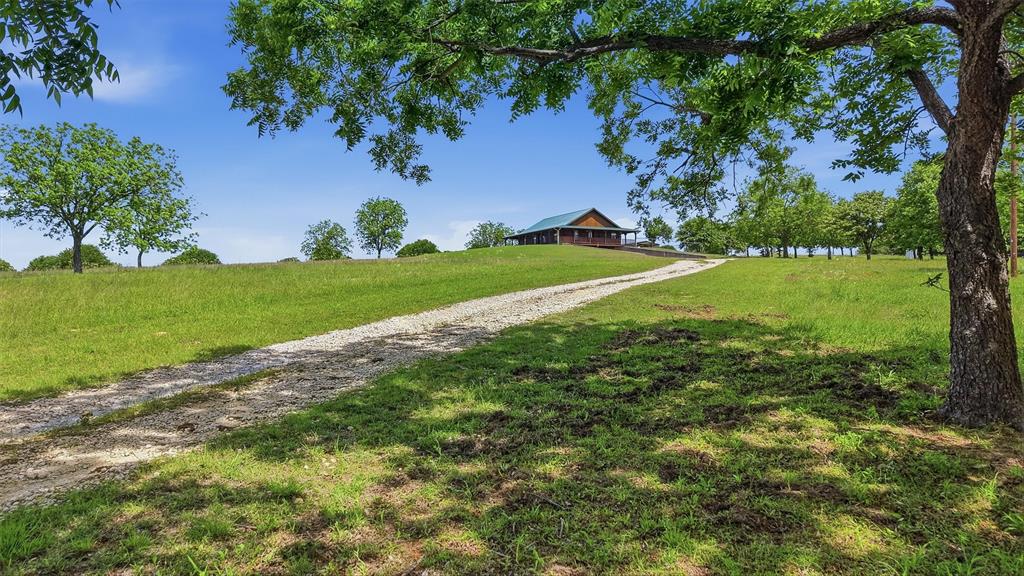 Charming hilltop, ranch style log cabin with full, covered wraparound porch on 7.39 scenic acres in Montague County, with beautiful views of the surrounding countryside, located in Saint Jo ISD. This Ranch Style Cabin features a full wraparound covered porch, 2 bedrooms & 2 full bathrooms on 1st floor with a half bath & 2 flex rooms in the basement that can be used as additional bedrooms, an office, sewing room or game room-man cave. HUGE garage with room for storage & work area. Large kitchen with island that open to the dining and living areas. Property also offers covered parking, septic system, propane and private well. Ideal for those seeking acreage with privacy while still enjoying modern conveniences. Plenty of room for animals, gardening, or future expansion. If you like peace & quiet with gorgeous country views then hurry out here!
