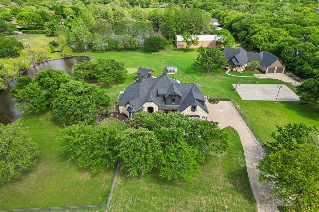 Country living meets luxurious comfort on this stunning 3+ acre estate in the heart of Argyle! This rare property features two fully custom homes, ideal for multigenerational living, guests, or a private office retreat. The main residence has been beautifully updated with remodeled bathrooms, fresh interior paint, upgraded kitchen, new windows throughout, and a full exterior renovation in 2024—including new roofs on both homes, updated stonework, enhanced landscaping, all new fencing, and a private electric gate for added security and convenience. Enjoy resort-style amenities like a sparkling pool with chiller (remodeled in 2024), a stocked pond fed by a private well, an outdoor kitchen, smoker pergola, greenhouse, putting green, and sport court. It’s an entertainer’s dream with space to relax, play, and host in total privacy. The second home built in 2017 is completely separate, offering full independence with its own kitchen, two bedrooms, two full bathrooms, a media room, spacious living area, and an oversized garage perfect for a boat or whatever else you need to store. Countless updates make this space ideal for extended family, a mother-in-law suite, guest quarters, or a dedicated home office. The property also features a 500-gallon buried propane tank (replaced in 2024), well water for irrigation and pond filling, and a peaceful setting that blends tranquility with convenience—just minutes from top-rated schools, shops, and restaurants. Horses are allowed in the neighborhood, offering true country charm just minutes from modern amenities. Located in the highly ranked Argyle ISD and close to Liberty Christian School, this estate offers the perfect balance of lifestyle, luxury, and location.