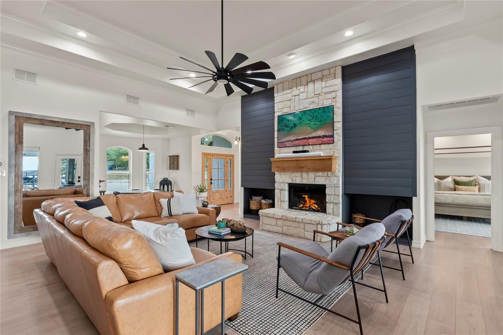 Stunningly renovated waterfront 2,920 sq ft home in Gun Barrel City on Cedar Creek Lake offering 4 bedrooms, 3 bathrooms, an oversized 2-car garage and open-water views. The spacious living room features large picture windows and a striking Austin-stone fireplace flowing into two dining spaces—a dedicated dining room (perfect place for combination dining game table) and a breakfast area. Connected to both dining areas, the open kitchen includes newer black stainless appliances with a convection oven and flat cooktop, a walk-in pantry,  island, and  bar seating for. Tall ceilings,  LVP flooring, decorative lighting, and a clean designer feel extend throughout. The waterside primary bedroom on the main floor features deck access, picture windows capturing open-water views, and electric blinds. The ensuite bath features a dual-sink vanity, walk-in shower with glass surround, soaking tub, and two walk-in closets. A second downstairs bedroom with full bath great for guests or full time living. Upstairs, an extra-large waterside bedroom includes a private waterside balcony, while another bedroom offers built-in bunks (two queens down, two twins up) and a walk-in closet. A full bath with a tub-shower combo serves both rooms. Outdoor living shines with a covered patio and extended deck with multiple seating areas, a hot tub, and a wrought-iron fenced yard that extends beyond the fence and includes a flagstone fire pit area. The boathouse features composite decking, modern railing, a party deck, lighting, and a cradle for a wake boat. Lake stairs allow easy water access, and a lake-pump sprinkler system. A large concrete driveway provides ample parking plus a two-car garage. Located in a desirable site-built community, the neighborhood includes a gated park with a boat launch, pavilion, and fishing pier, with easy access to Gun Barrel City shopping and dining. Short term rentals allowed with permit from Gun Barrel City. Furnishings and Watercraft available separately.