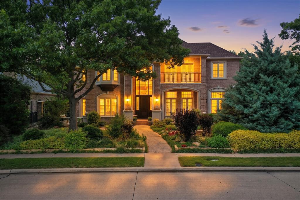 Nestled within the prestigious enclave of Lakeside on Preston, this 5,998-square-foot estate offers more than just a residence—it offers a lifestyle defined by elegance and natural beauty. Positioned on a premier lot with tranquil lake and park views, the home commands attention with its stately curb appeal. A deep, covered front veranda and a classic upstairs balcony overlook the tree-lined street, inviting you to enjoy the quiet rhythms of one of Plano’s most coveted neighborhoods. Upon entry, the home reveals its architectural pedigree through a grand staircase, soaring ceilings, and expansive windows that flood the space with light. The heart of the home is a designer kitchen balancing style and high-end function, featuring a six-burner Dacor gas range with double ovens, built-in refrigeration, and a back staircase for discreet access. This space flows into a breakfast nook that opens to a side patio, and a cozy den anchored by a fireplace and walk-in wet bar. For those who work or exercise at home, the property offers a rich wood-paneled study with French doors and a separate bonus room with hardwood flooring and mirrors, ideal for a gym. Upstairs, a massive game room features its own balcony, a second walk-in wet bar with a fridge and dishwasher, and ample space for a pool table. Adjacent is a dedicated media room for a true cinema experience. The primary suite serves as a private sanctuary, featuring a sitting area, a gas fireplace, and bay windows with direct patio access. The ensuite is a masterclass in luxury with dual vanities, a hydrotub, and a rare hidden safe room. Outside, the resort-style oasis has a heated pool and spa and a garden sitting area under mature trees. The covered patio offers a fireplace and built-in grill station to provide the ultimate setting for al fresco dining. With tons of storage, a large floored attic, and access to community lakes, trails, and tennis & pickleball courts, this home is a rare masterpiece of design and comfort.