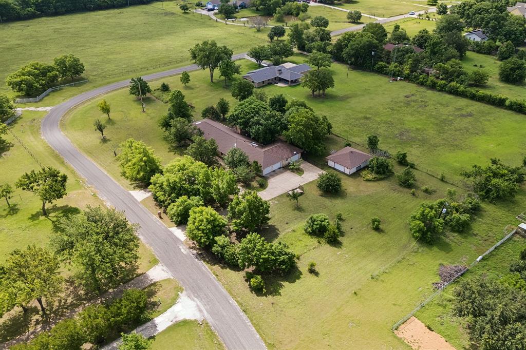 Enjoy the freedom and flexibility of quiet country living on almost 2 acres while staying just minutes from all the conveniences McKinney has to offer. Situated at the back of a 1-street neighborhood on a corner lot with a circular driveway, this unique property has been thoughtfully expanded over the years to accommodate every lifestyle. The main home is a 3-bed, 2-bath, 2-car garage home that was just fully renovated. Attached to the garage is a private-entry 1-bed, 1-bath apartment or MIL suite with its own 1-car garage. Detached from the main building is a 30' x 25' shop with an exercise room and a half bath. Inside the primary house, you’ll find tons of newly-renovated features like LVP and wood flooring throughout the main living areas, all new paint, new fixtures, a kitchen featuring quartz countertops, new cabinets, a large island, and a walk-in pantry. The spacious primary suite offers dual closets and a spa-like bathroom with a large walk-in steam shower and a rainfall shower head. The floor plan is as versatile as it gets, with a huge 2nd living or game room, as well as an office or 3rd living area with wood floors. A cozy wood-burning fireplace in the main living area provides the perfect space to relax, while the oversized game room offers endless possibilities for entertainment and family fun. Additional improvements include a breezeway and a huge 25x29 main garage, plus a covered back patio with additional open-air outdoor living space for enjoying Texas sunsets. Need room for guests, hobbies, or multi-generational living? The attached 1-bed, 1-bath MIL suite or apartment includes a large living-sleeping area and is already plumbed for a future kitchen and laundry. A detached workshop with a half bath and dedicated exercise room adds even more versatility. Whether you’re looking for space to spread out, work from home, accommodate family, or pursue your passions, this one-of-a-kind property offers the flexibility you’ve been searching for.