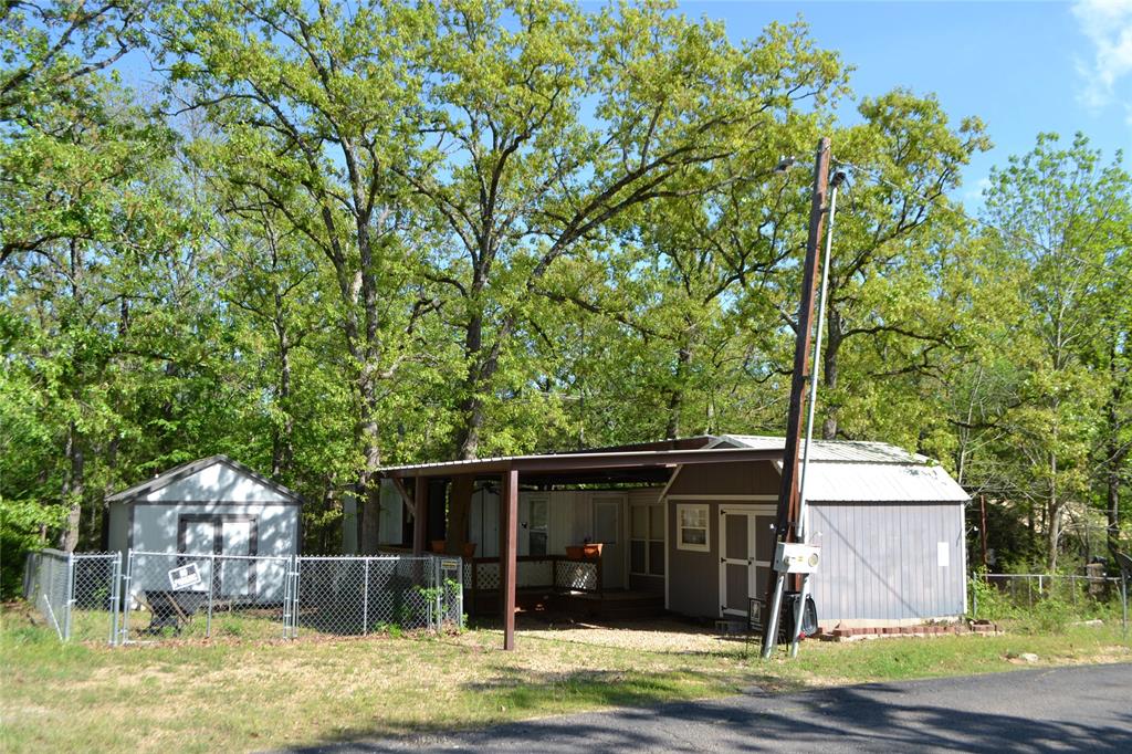 Lots 91 & 92, Section 2 in Sun Eagle Bay offer a great opportunity to own two lots in a gated waterfront community on Lake Fork. This property features an older park model in good condition, ideal for weekend getaways, full-time living, or a fishing retreat. The park model includes a full-size refrigerator and full-size range, along with a recently added full-size washer and dryer area for added convenience. A metal RV awning covers the park model, deck, and parking space, providing excellent protection from the elements. The property also offers a chain-link fenced area suitable for pets. Two storage sheds convey with the property. One shed has been finished out with electrical outlets and a window unit, making it suitable for a workshop, hobby space, or additional flex area. Sun Eagle Bay is a gated community with amenities that include a community pool, playground, boat ramps, and fishing pier, offering easy access to the Lake Fork lifestyle. This property provides flexibility, functionality, and access to desirable community features in a well-established lakefront neighborhood.