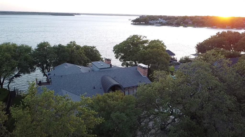 A rare expression of timeless luxury on the water, this extraordinary 5,268-square-foot lakefront estate seamlessly blends classic architecture with refined modern updates—including a new roof for added peace of mind. Originally built in 1980 and thoughtfully reimagined, this multi-level residence is designed to capture sweeping lake views from nearly every vantage point.
Featuring 5 bedrooms and 5.5 baths, each private suite offers its own entrance and breathtaking waterfront views—creating an atmosphere of secluded comfort for both residents and guests.
At the heart of the home, an elegant library showcases a full wall of floor-to-ceiling custom built-ins, complete with a rolling ladder, all framed by tranquil lake views—an inspiring space equally suited for work or quiet reflection.
The home’s expansive design unfolds into three distinct living areas, each offering its own ambiance for gathering and entertaining, while three fireplaces, including one in the primary suite, infuse warmth, character, and a sense of intimacy throughout.
The primary suite is a true sanctuary, highlighted by a striking, spa-inspired bathroom where a centrally positioned jetted tub creates a dramatic focal point. Designed for both relaxation and indulgence, this space is complemented by an exceptionally large walk-in closet, offering boutique-style storage and organization. A private fireplace within the suite adds an additional layer of comfort and luxury.
Entertaining is effortless with a spacious chef’s kitchen, formal dining room, and a resort-style outdoor setting featuring a sparkling swimming pool—perfect for hosting unforgettable gatherings.
Down at the shoreline, a substantial private boat dock delivers the ultimate lakefront lifestyle, thoughtfully designed to accommodate multiple boats and jet skis with ease—inviting endless days on the water.
This is more than a home—it is a private waterfront family retreat