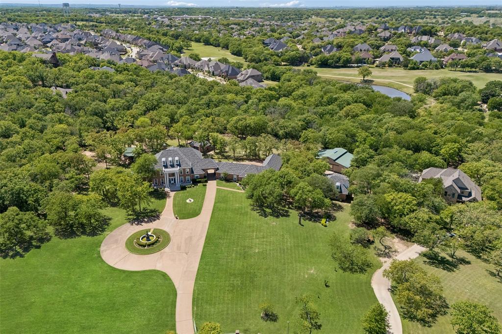 Step into timeless elegance at this stunning Georgian Colonial estate, gracefully set on 8.134 gated acres in the coveted Canyon Oaks enclave. Designed for discerning buyers seeking sophistication, space & self-sufficiency, this remarkable property offers a rare blend of grandeur, functionality, & flexibility, ideal for multi-generational living or a private family compound. From the moment you pass through the gated entrance, the circular drive, manicured lawns & stately fountain welcome you home. The main residence exudes classic architectural charm paired w-modern luxury, featuring expansive living spaces filled w-natural light & panoramic views of the resort-style pool & tranquil wooded surroundings. Perfect for entertaining, the home’s open flow leads to multiple gathering rooms, a chef’s kitchen + elegant formal & casual spaces for every occasion. Luxurious primary suite offers a private retreat w-its own steam shower + built-in sauna, along with room for exercise equipment or a serene sitting area. Separate mother-in-law or nanny suite provides comfort & privacy for extended family, while the 515 sq. ft. studio apartment & garage apartment offer additional options for guests, income, or creative workspaces. Outdoors, this estate transforms into your personal resort. A sparkling pool & hot tub are accompanied by a 350 SF cabana house, a covered outdoor kitchen w-FP + a pizza oven along w-a charming 200 SF kids’ playhouse or greenhouse—every generation has their place to relax & play. The 1,900 SF workshop with a professional car lift is a dream for hobbyists. With ETJ zoning & no city taxes + a voluntary HOA, this property offers exceptional freedom & value. The attached 1.41-acre platted lot adds even more potential for future building or investment. Ideally located just minutes from Highland Village, Bartonville, Lantana, and Liberty Christian School, you’ll enjoy the best of both worlds—peaceful country living with upscale conveniences close at hand.