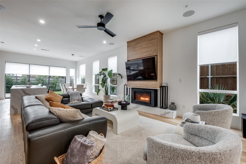 Nestled on a quiet, tree-lined block in the heart of Dallas, this architecturally curated home offers a combination of luxury and livability, within walking distance to both Henderson Avenue and Lower Greenville. Completed in 2022, this light-filled modern was designed with intentionality. White oak hardwood floors anchor an open floor plan that flows beneath 10ft ceilings, while an abundance of natural light pours through thoughtfully positioned windows. Level 4 finish walls, custom roller shades, and a dramatic floating metal staircase speak to the caliber of craftsmanship found throughout. The main living area is centered around a gas fireplace with a sleek quartz surround, opening gracefully into a dining space appointed with a custom light fixture — a natural gathering place designed for both intimate evenings and elegant entertaining. The chef's kitchen is nothing short of exceptional, featuring an oversized quartz waterfall island with counter seating, fully custom cabinetry, and a suite of premier appliances including a built-in Fisher & Paykel refrigerator-freezer, Gaggenau dishwasher as well as a microwave and a six-burner gas range with oven. Glass panel stacking doors dissolve the boundary between indoors and out, leading to a landscaped private backyard complete with a fireplace, patio, and an integrated six-speaker audio system — four inside, two al fresco — setting the stage for year-round outdoor living. A first-floor powder room dressed in custom Gucci wallpaper adds a moment of playful sophistication. A gated entry ensures both security and privacy throughout. Upstairs, a skylit corridor guides you to three well-appointed bedrooms, including an oversized primary suite with a spa-caliber bath featuring a soaking tub, glass-enclosed shower, and a generous walk-in closet. A dedicated second-floor utility room offers full-size stackable laundry and additional storage. An oversized two-car garage completes this impeccably considered home.