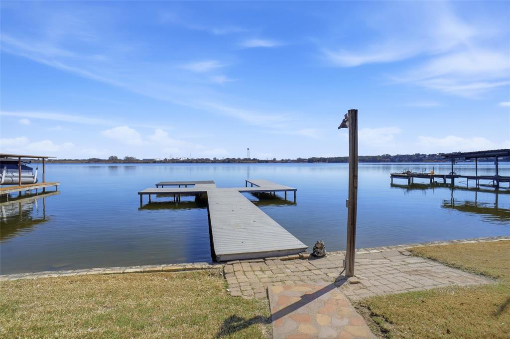 Motivated seller! Fantastically maintained LAKEFRONT property on Lake Granbury. Make memories that last a lifetime! This 3-bedrm, 2 bathroom retreat, perfectly positioned directly on the MAIN BODY of Lake Granbury. If you're looking for big water views and deep water access, this is the one! The interior is designed for both relaxation and entertaining, featuring two living areas that provide ample space for guests to spread out. A cozy wood burning fireplace offers the perfect focal point for chilly evenings after a day on the water. The eat in kitchen complete with space for a table & breakfast bar seating, & flows seamlessly into the two main living spaces, making morning coffee with a view a true luxury. Ensuite owners retreat &  good size secondary bedrooms for room to spread out & have guests stay! The outdoor amenities truly set this property apart. Step out onto the spacious covered deck, an ideal vantage point for shaded afternoons, sunset evenings or late night stargazing over the open water. This home is fully fenced offering a secure environment for pets or play. Convenient storage shed for all your lake gear and fishing tackle. Parking is a breeze with the gated double carport, providing protection for our vehicles and toys. Water enthusiasts will fall in love with the private dock which was added in 2022 & 23 and ready for you to add your canopy and lift. Just out your back door is immediate access to boating, wakeboarding, fishing, floating, and sunset cruises.  Nestled in a wonderful established neighborhood you'll enjoy the peace of a private oasis alongside fantastic community amenities.   Whether looking for a full time residence or a weekend getaway, this home offers the perfect setting to make great memories on the Lake. Don't miss your chance to own a piece of Lake Granbury's most sought after shoreline! Boat and home furnishings are negotiable.  Home is Certified Manufactured home. Please see Offer Guidelines in Transaction Desk.