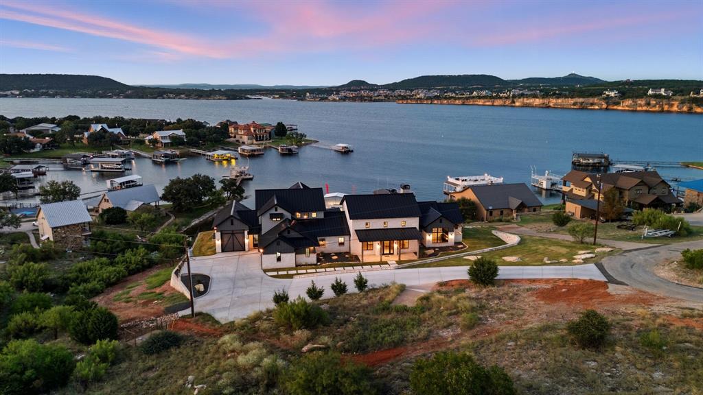 Stunning new construction home offering unparalleled lake views and exceptional design throughout. This thoughtfully designed residence features 5 spacious bedrooms, each with its own en suite bath, vaulted ceilings, and two generous living areas ideal for entertaining and relaxing. The gourmet kitchen includes an eat-in dining area and butler's pantry for added convenience. Enjoy true lakefront living from the enormous covered patio complete with a full outdoor kitchen and resort-style pool, all perfectly positioned to capture the breathtaking scenery. Attached garage provides ultimate functionality for lake enthusiasts! A rare opportunity to own a luxury lakefront retreat with premium amenities and incredible views.