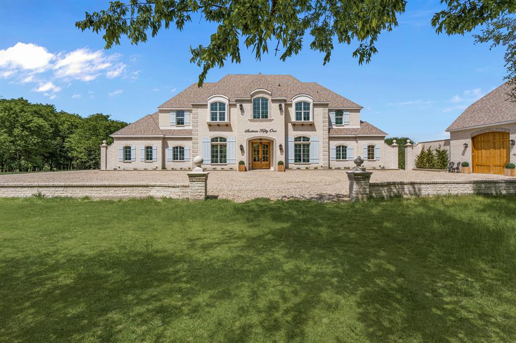 Tucked behind beautiful private gates and a canopy of towering trees on 10 pristine acres in Aledo, this extraordinary French Country estate offers a rare blend of privacy, craftsmanship, and thoughtful design just five minutes from Press Café and I-20. A grand entry foyer welcomes you with light checkered tile flooring, soaring ceilings, flanked by a formal dining room and designated study. Beyond the foyer, the home opens into the heart of the living spaces where dramatic cathedral ceilings in the living room and kitchen create an incredible sense of scale and light. The chef’s kitchen, accented with warm brick and stone, features a massive island, butler’s pantry, and herringbone wood floors that continue into the living area. Picturesque windows throughout fill the home with natural light and frame views of the surrounding acreage. The living room is anchored by a grand floor-to-ceiling stone fireplace, flanked by built-ins with brick accents. One of the home’s most unforgettable spaces is the grand bibliothèque an extraordinary library featuring dual fireplaces, custom built-ins, a full bar with ice machine and refrigerator, creating the perfect setting for entertaining or quiet evenings. Entertainment continues with a first-floor theater room. The primary suite, features paneling, rich hardwood floors, a fireplace, while the spa-inspired bath showcases polished neutral checkered flooring, a walk-through brick shower, and a freestanding soaking tub. Separate his-and-her closets provide exceptional storage. A laundry within the primary closet adds everyday convenience. Built with exceptional efficiency, the home is fully encapsulated with spray foam insulation for year-round comfort. Additional highlights include a five-car garage, spacious guest suites, and a thoughtfully designed floor plan with no wasted space. A survey, pool renderings, and build plans are available upon request. Select furnishings are available to purchase upon request.