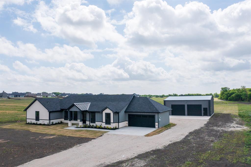 Country living within short distance to the City. Set on a 1.465-acre tract, this new constructed modern farmhouse offers country living with convenient access to the city. The property provides open views and a rural setting while being located just minutes from shopping, dining, and schools in Waxahachie. The home features an open-concept layout connecting the living, dining, and kitchen areas. Multiple well-placed windows bring in natural light and provide views of the surrounding land. The kitchen includes quartz countertops and functional workspace for everyday use. The property also includes a 1,600-square-foot shop, suitable for a variety of uses such as storage, equipment, vehicles, or workspace. The shop is equipped with a private half bathroom for added convenience. MUST SEE